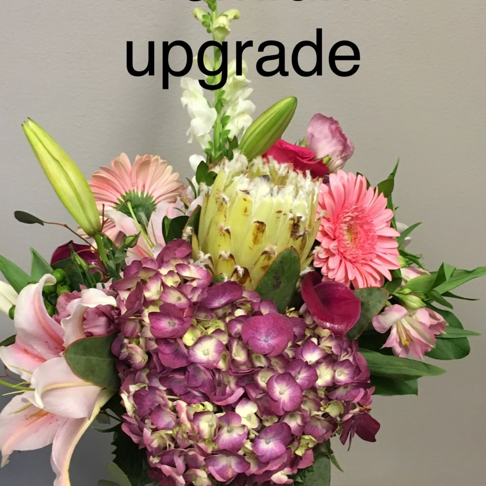 Mixed bouquet with pink lilies, gerbera daisies, hydrangea, and a protea