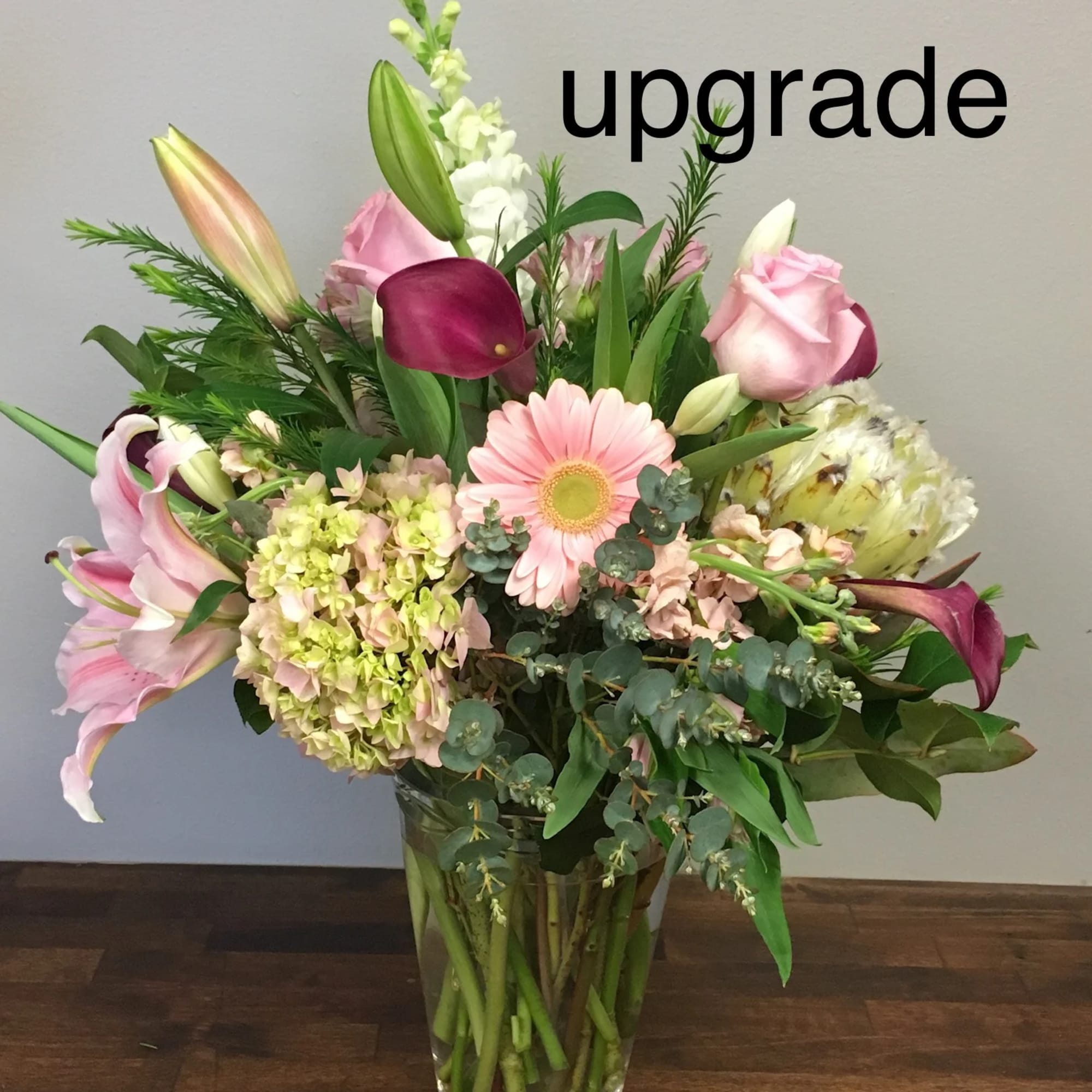 Mixed bouquet in a glass vase with pink lilies, roses, and a gerbera daisy