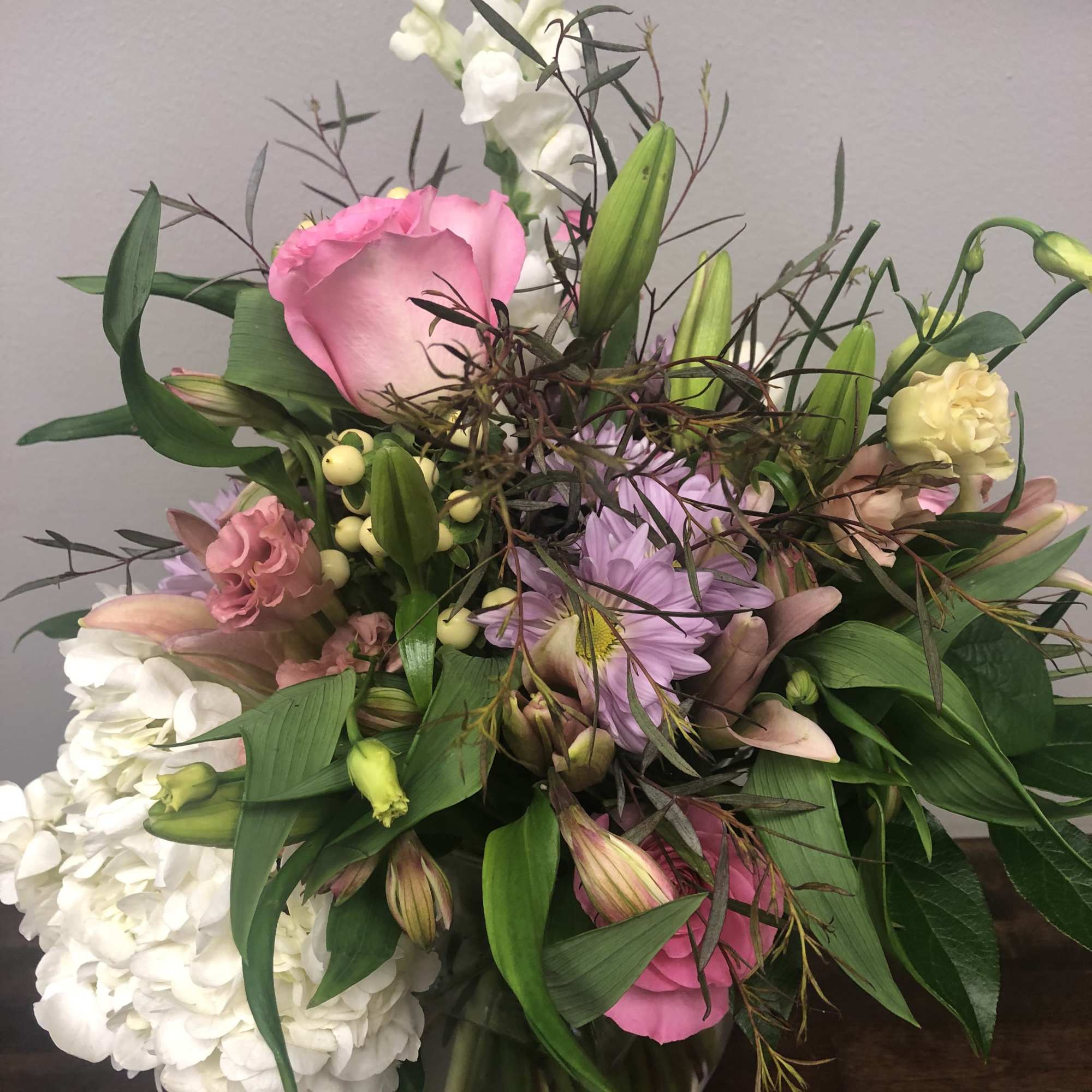 Mixed pink, white, and lavender flowers in a glass vase