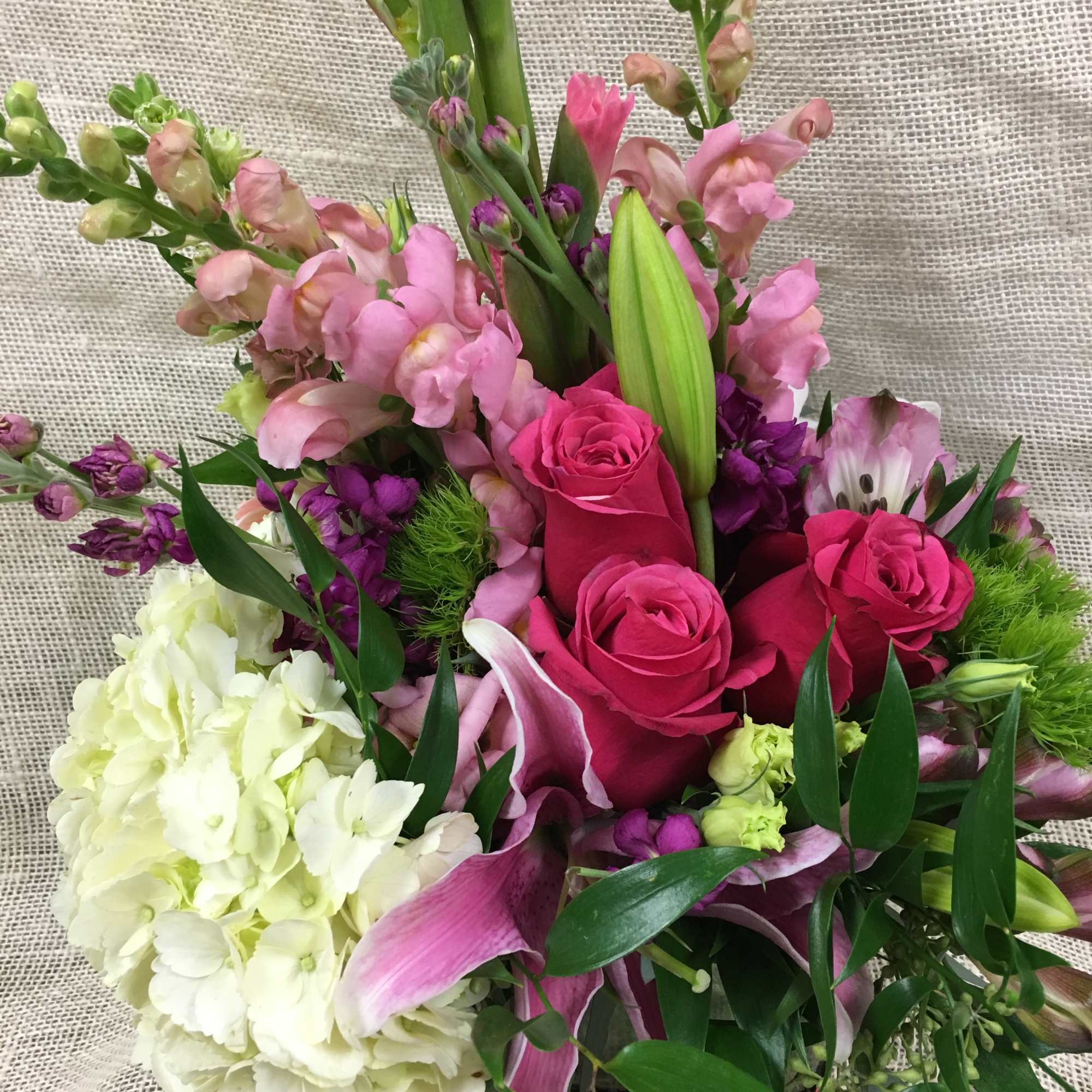 Bouquet of pink roses, lilies, and white hydrangea with purple accents