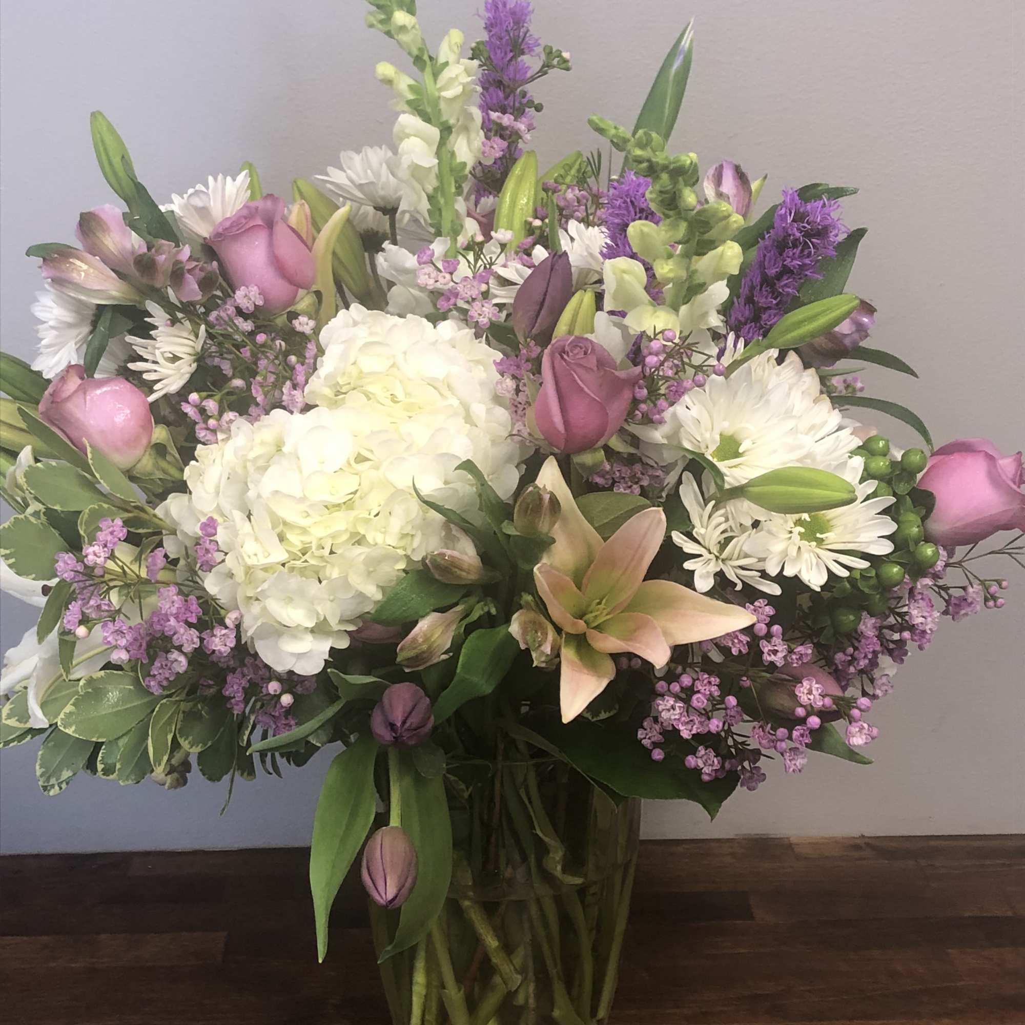 Mixed bouquet of white, pink, and purple flowers in a glass vase