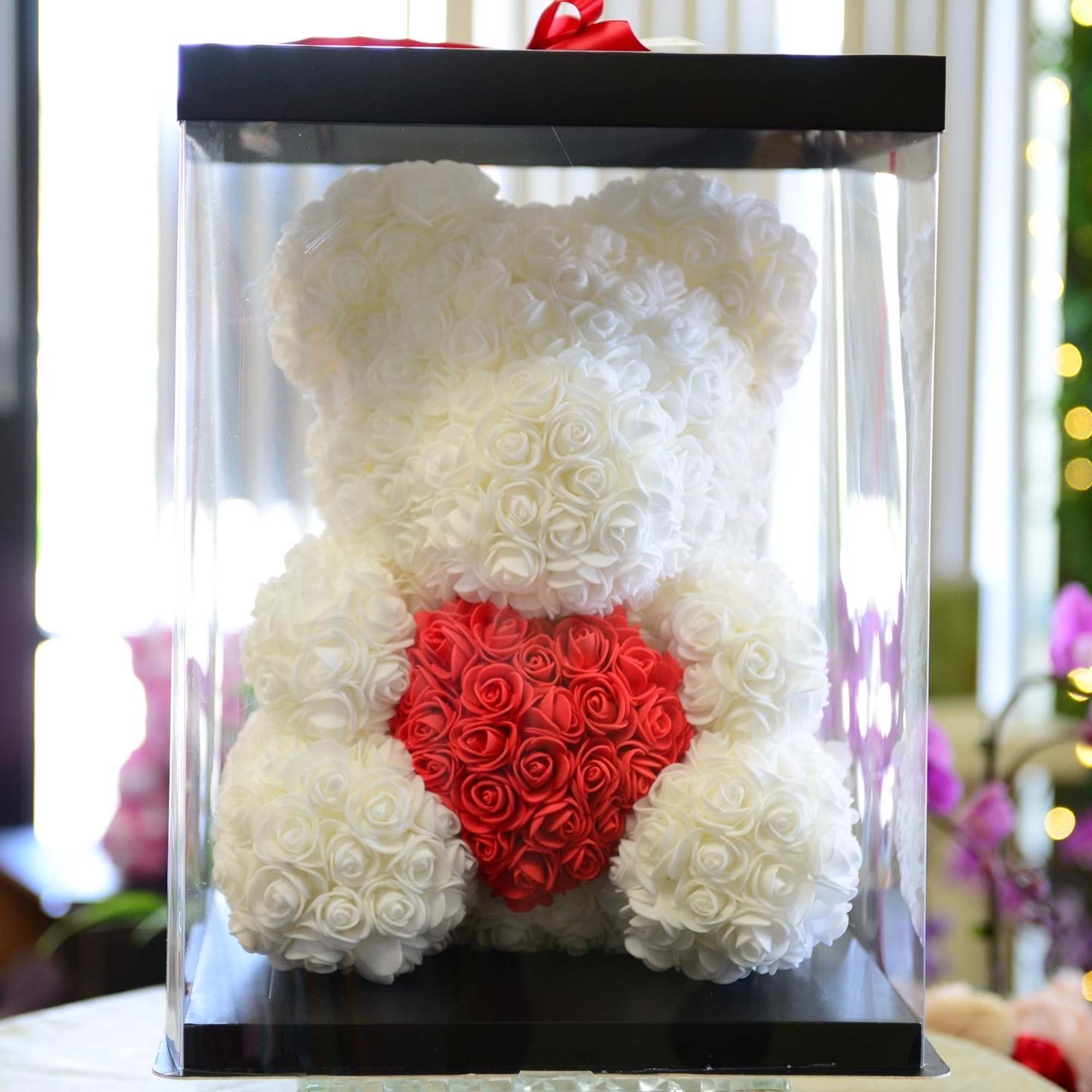White teddy bear made of roses with a red heart in a clear display box