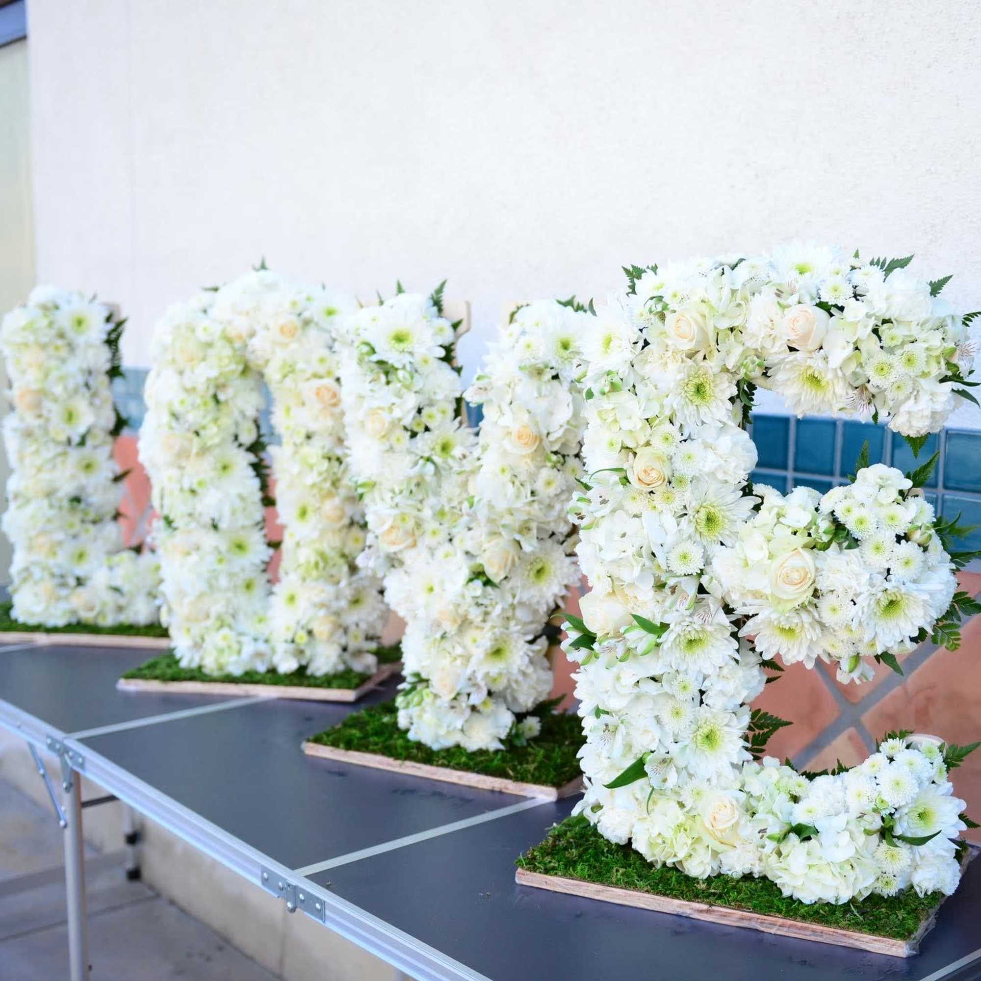 White floral letter arrangements displayed on a table