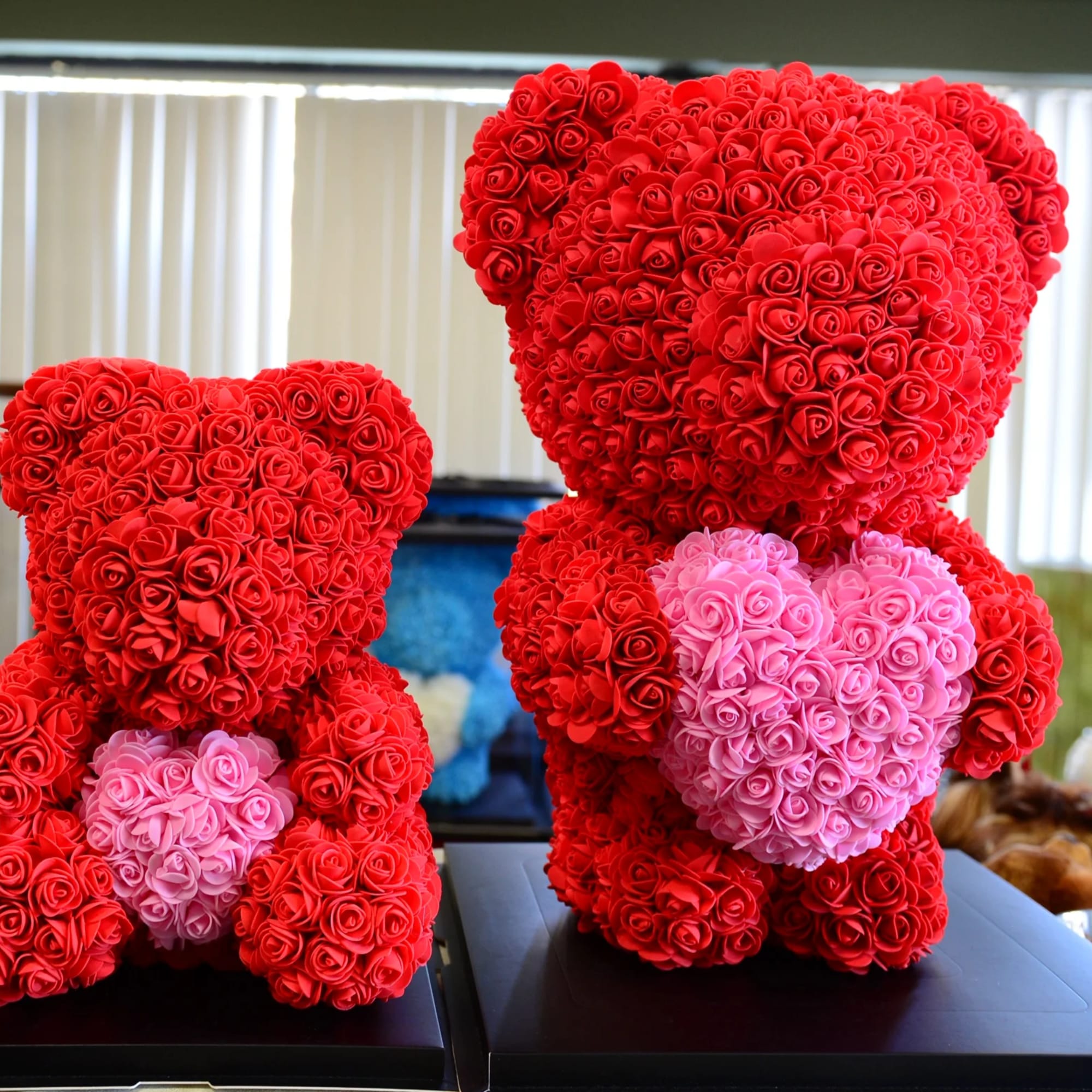 Two teddy bears made of red and pink roses on black bases