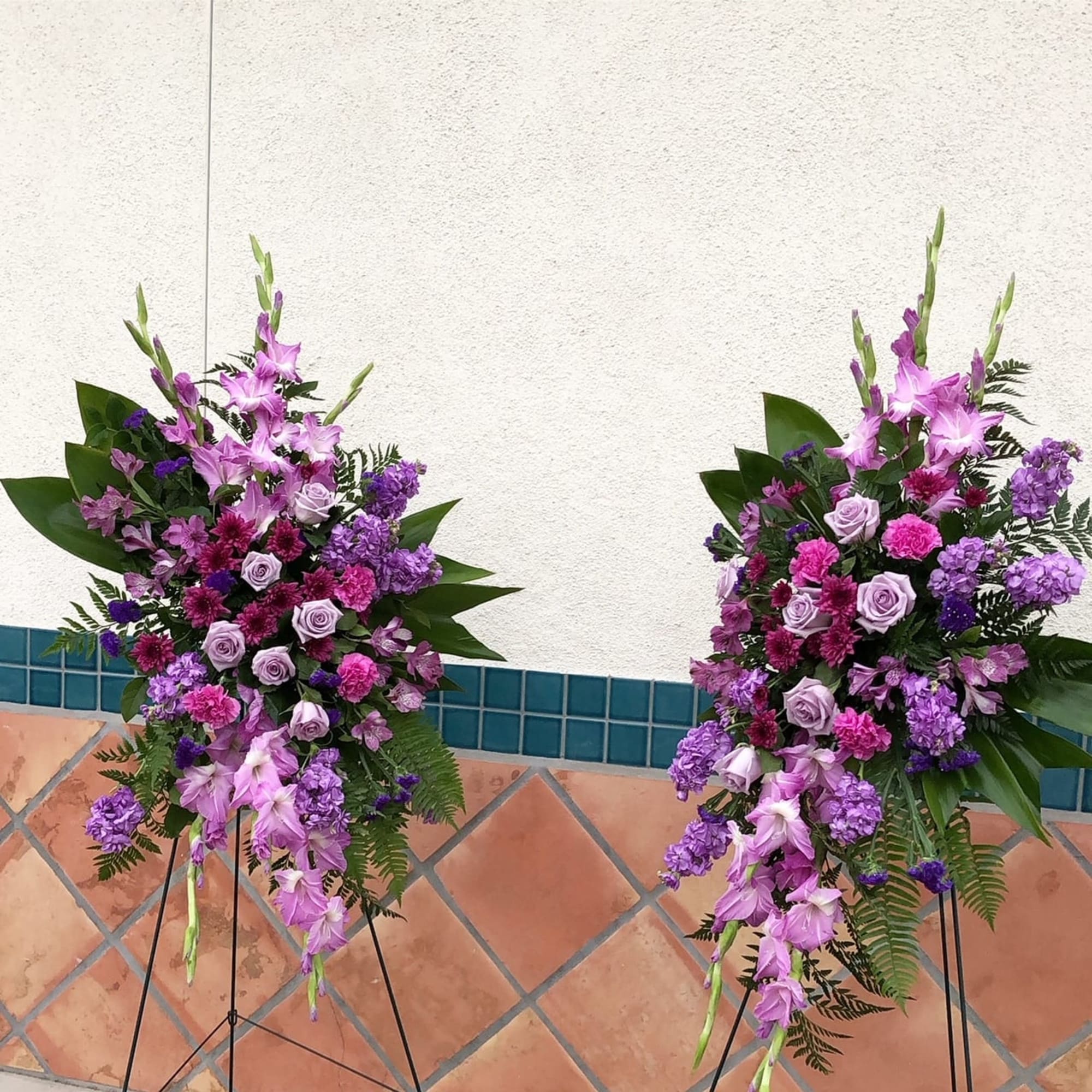 Two tall purple floral standing sprays on black easels