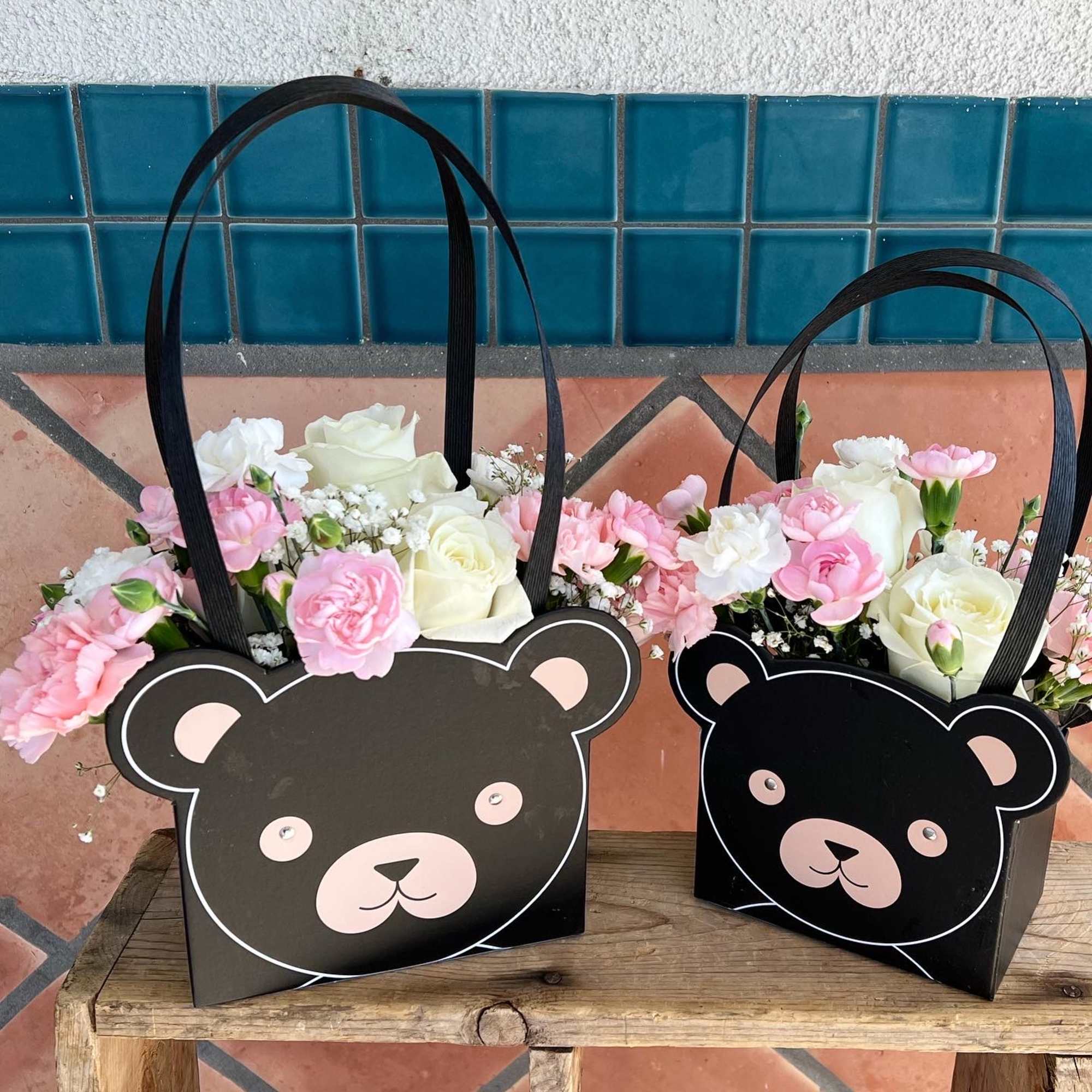 Two black bear-face gift bags filled with pink and white flowers