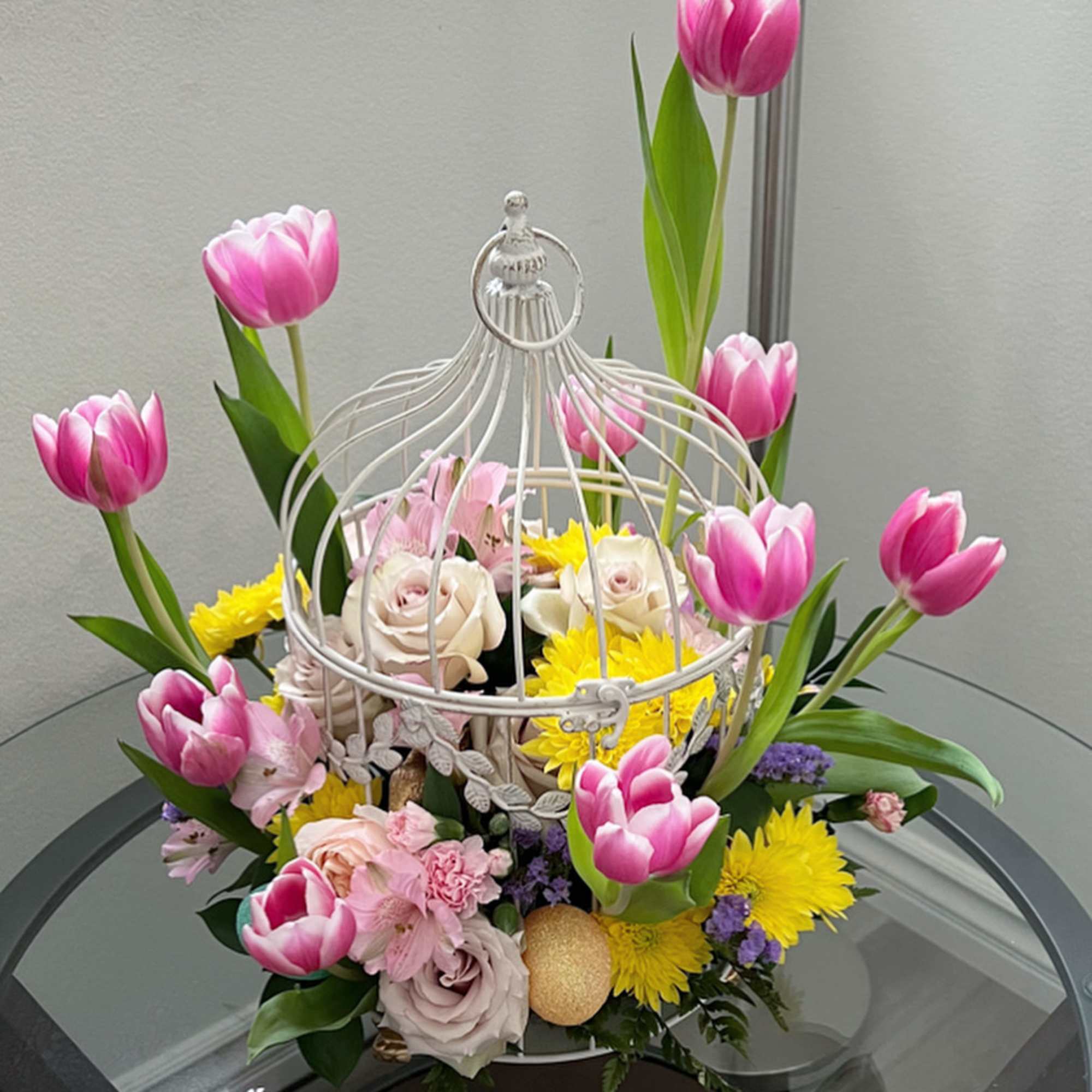 Pink tulips and mixed flowers arranged in a white birdcage centerpiece