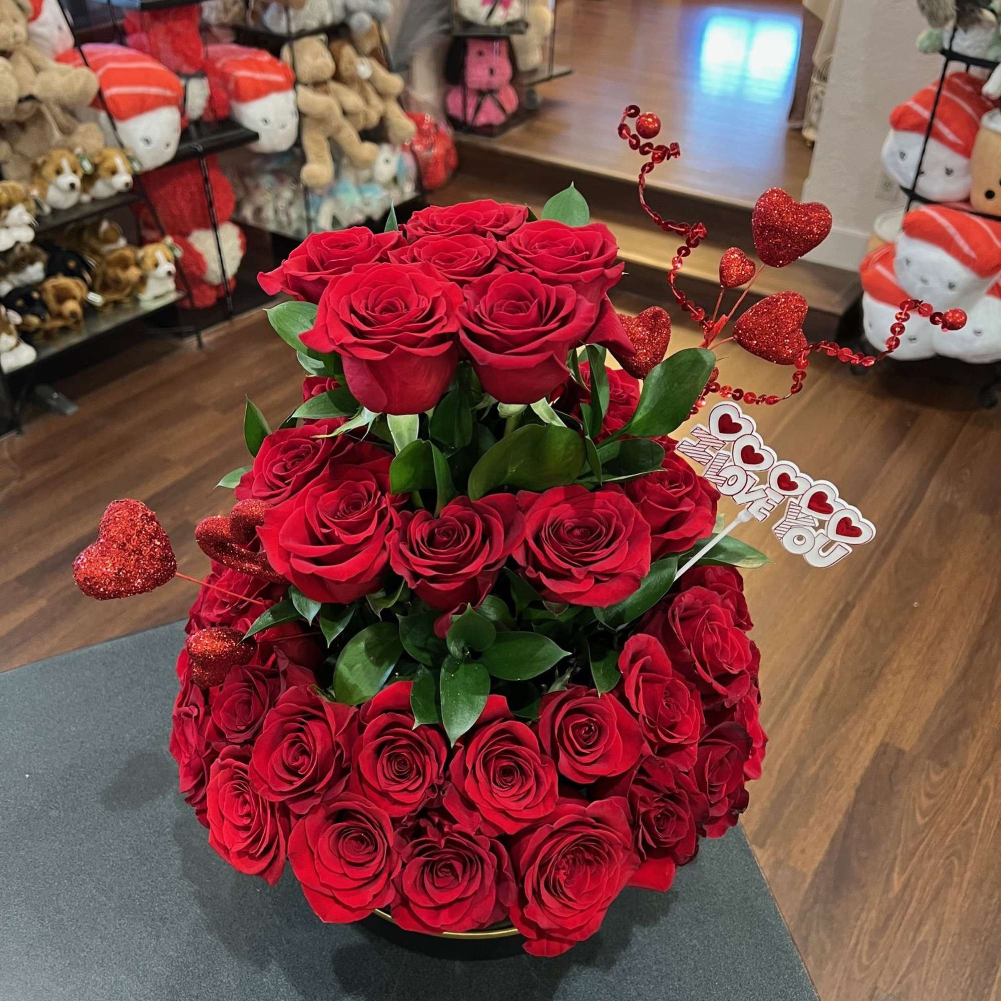 Tiered arrangement of red roses with heart decorations and a love sign