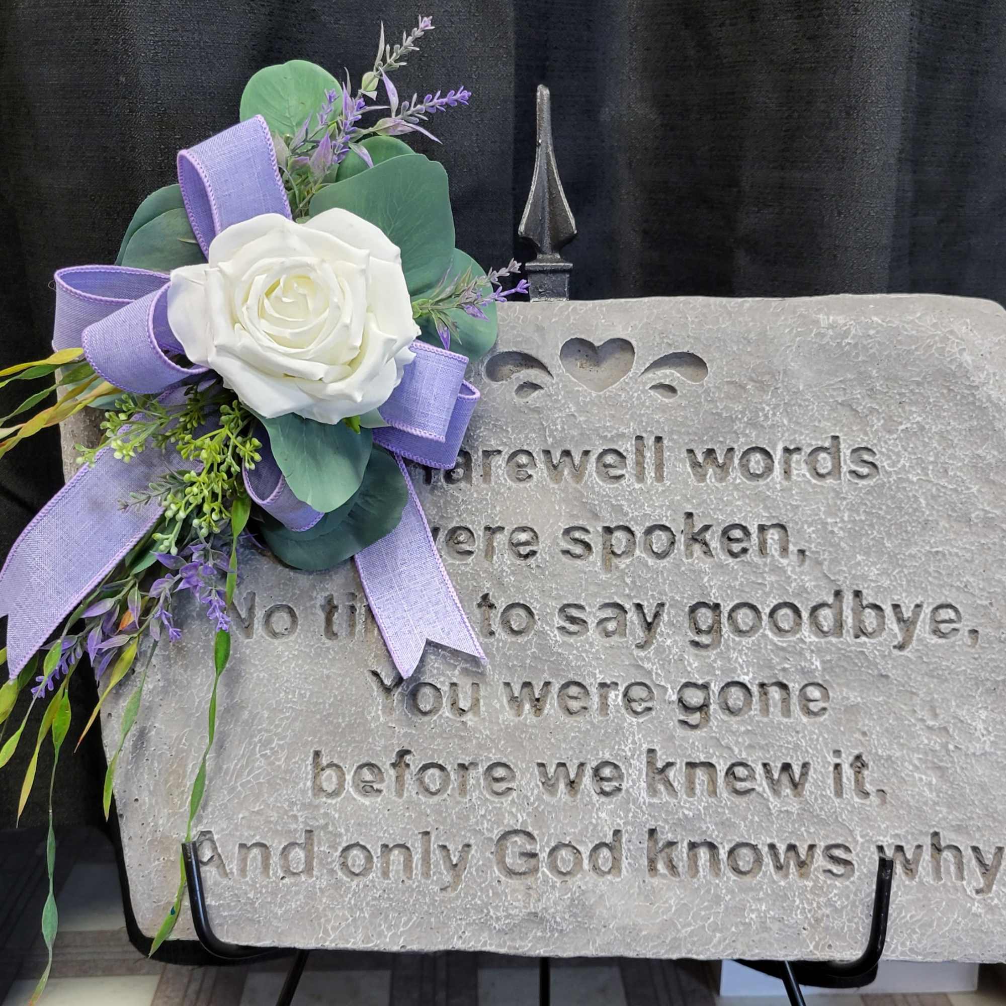 White rose corsage with lavender ribbon on a memorial stone