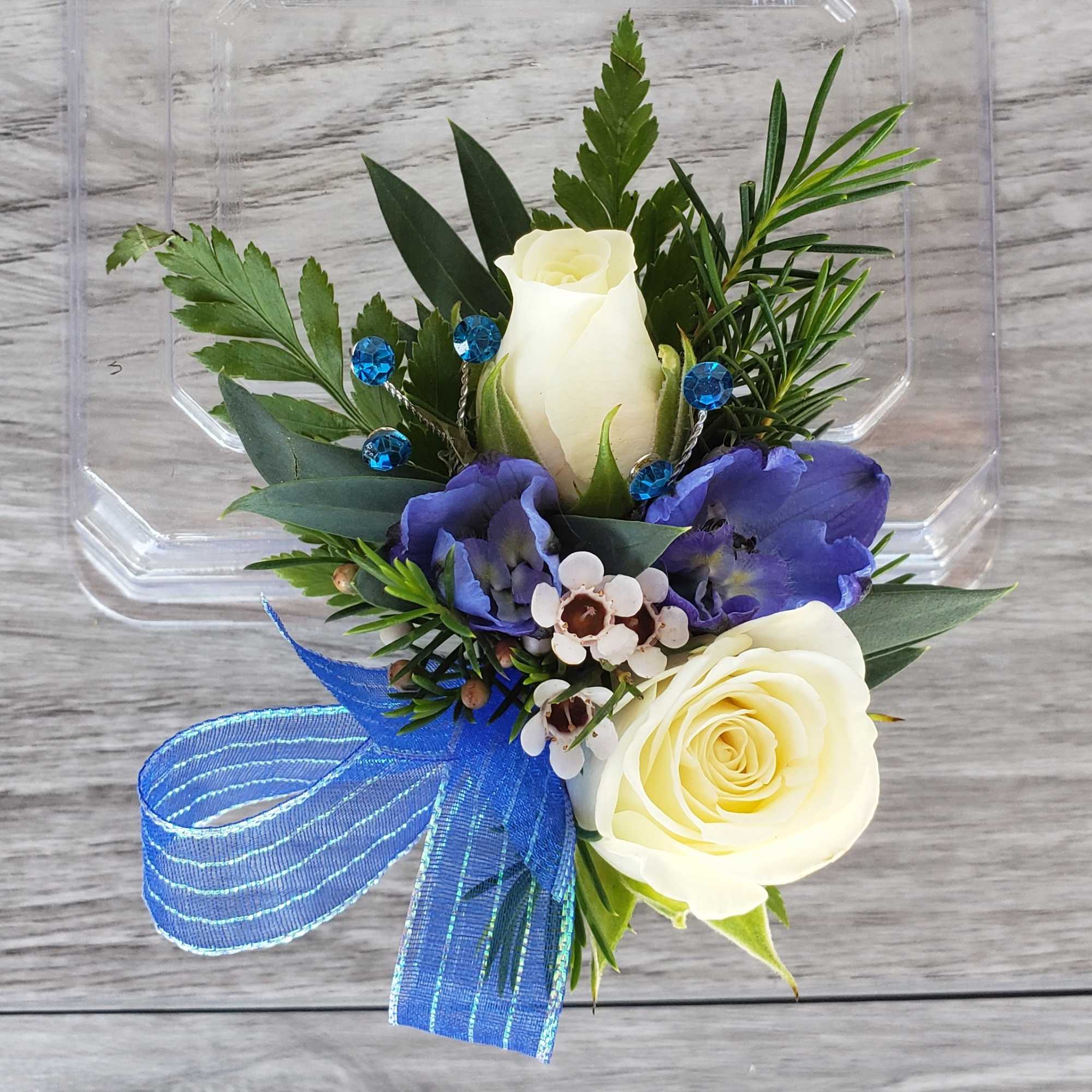 Small bouquet with white roses, purple blooms, and a blue ribbon