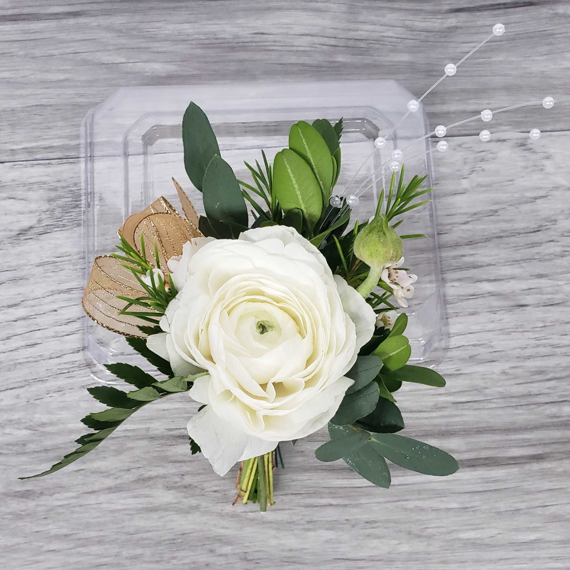 White ranunculus boutonniere with greenery and ribbon accents