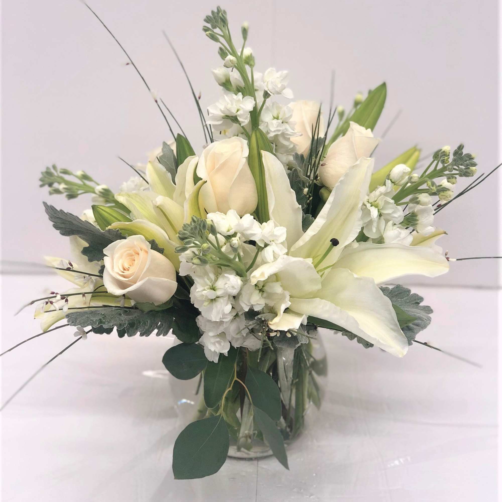 White roses and lilies in a clear glass vase