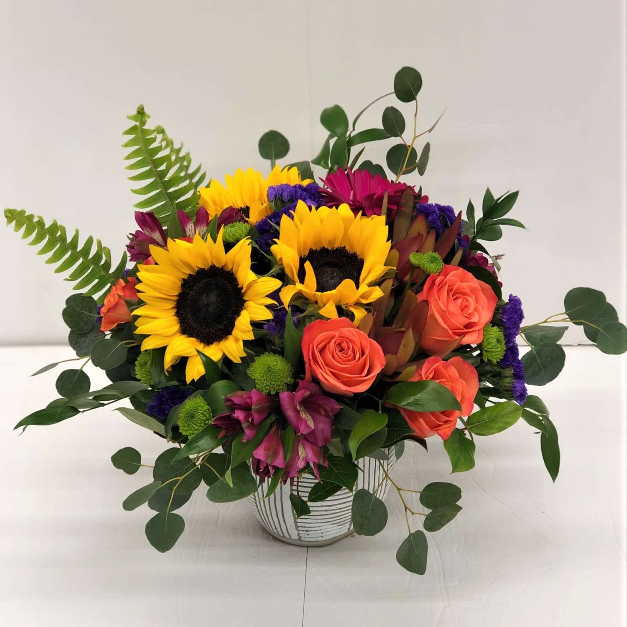 Bouquet of sunflowers and coral roses in a striped vase