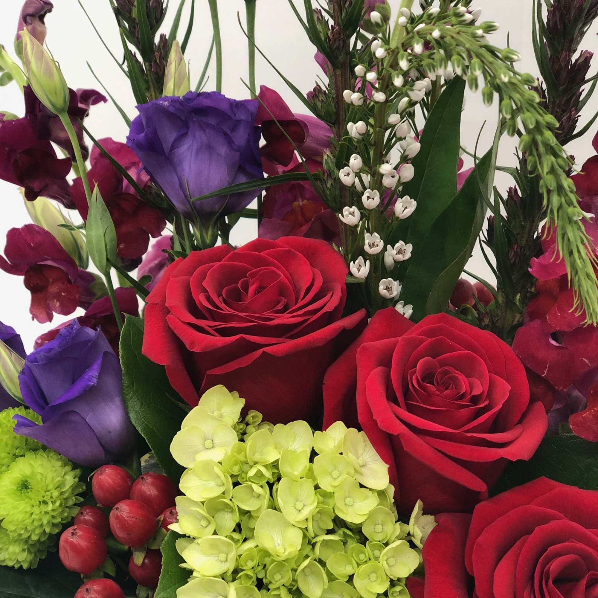 Bouquet of red roses, purple lisianthus, and green hydrangea