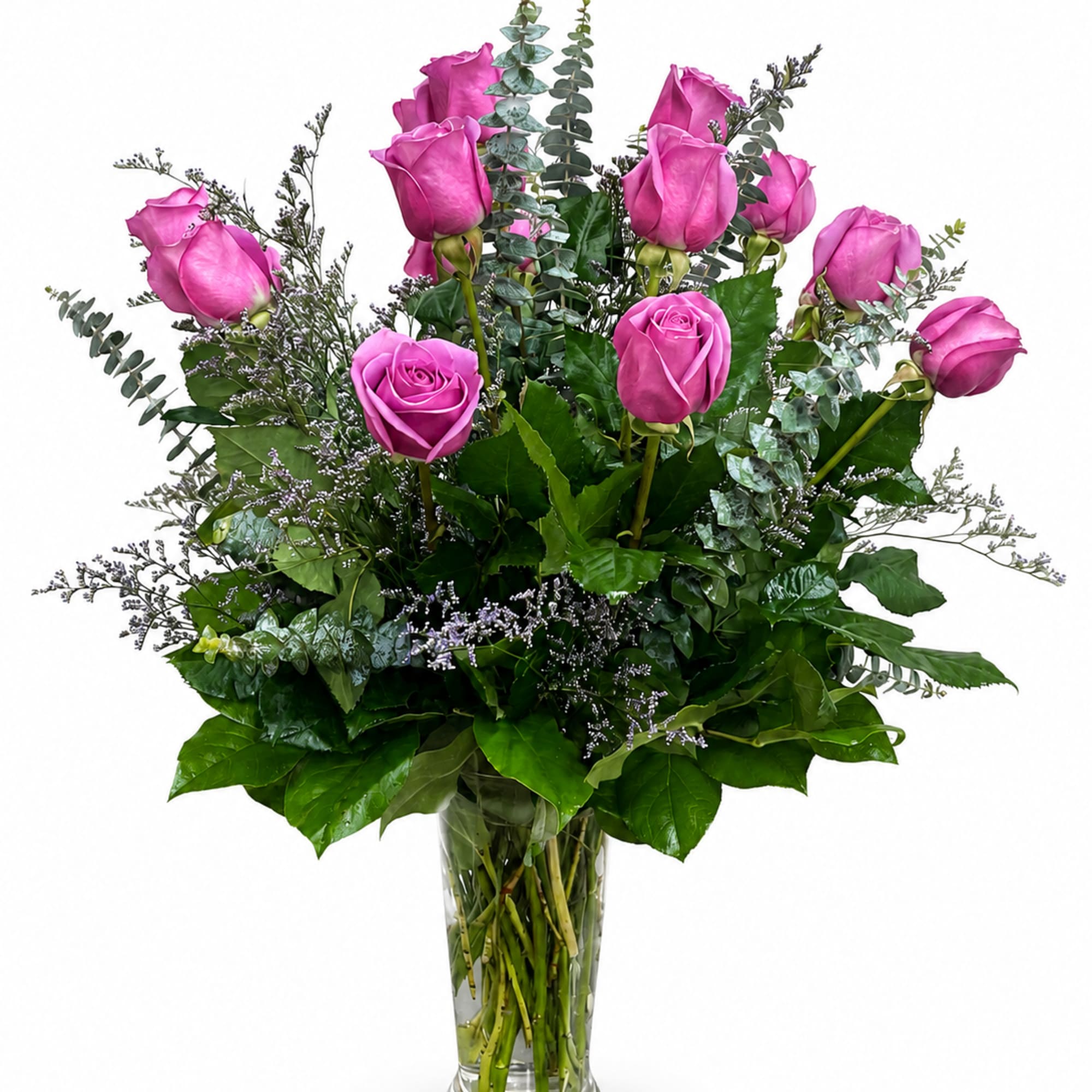 Pink roses arranged in a clear glass vase with mixed greenery