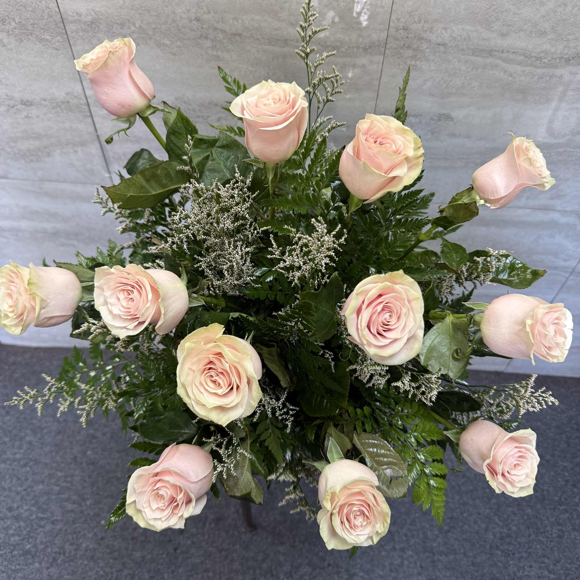 Arrangement of pale pink roses with greenery in a vase