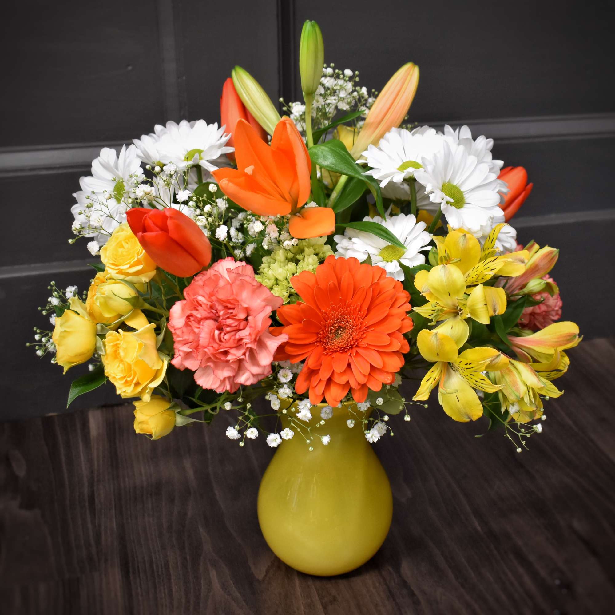 Colorful mixed bouquet in a yellow vase with daisies, roses, and lilies