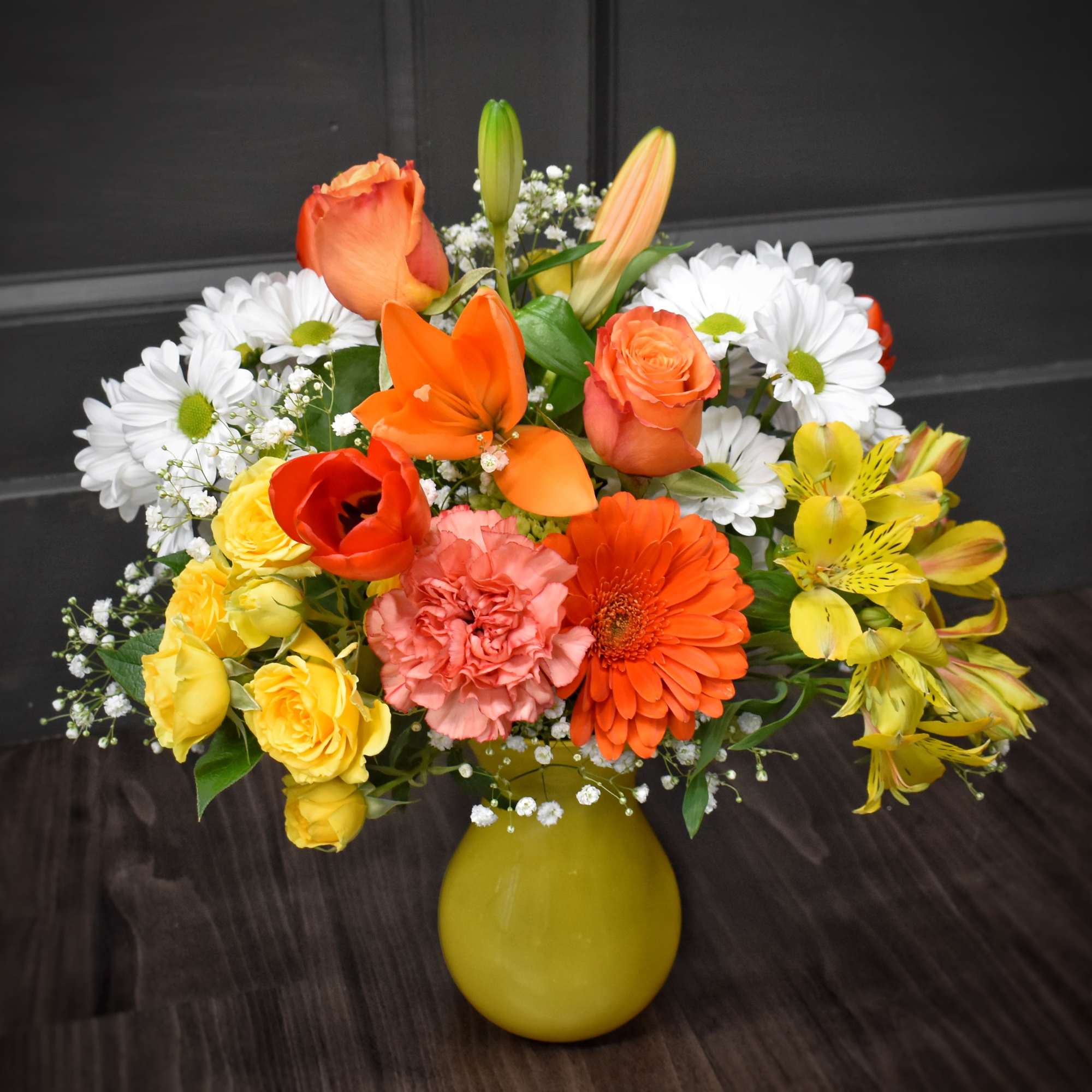 Mixed bouquet in a yellow vase with roses, lilies, daisies, and gerbera daisies