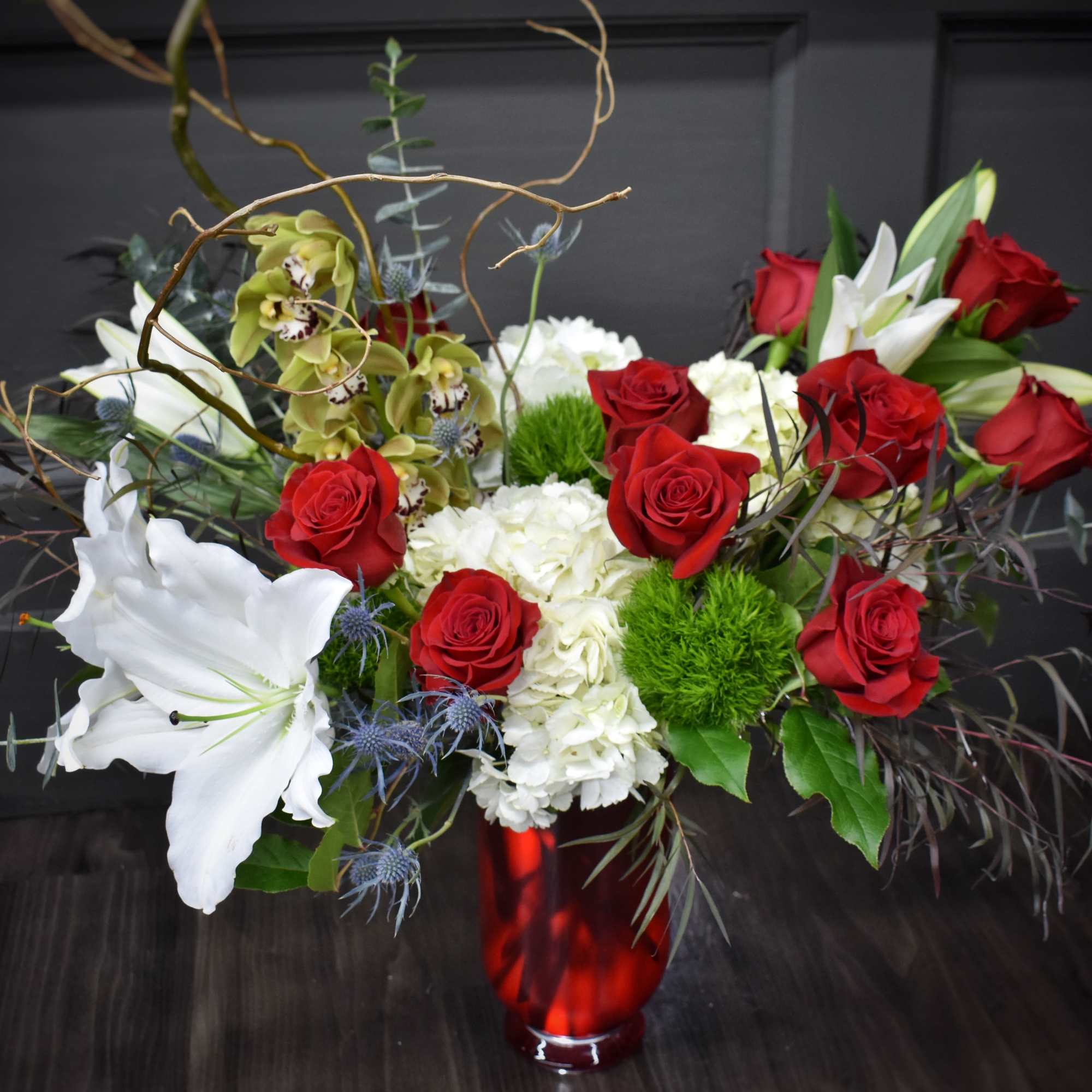 Red roses and white lilies in a red glass vase