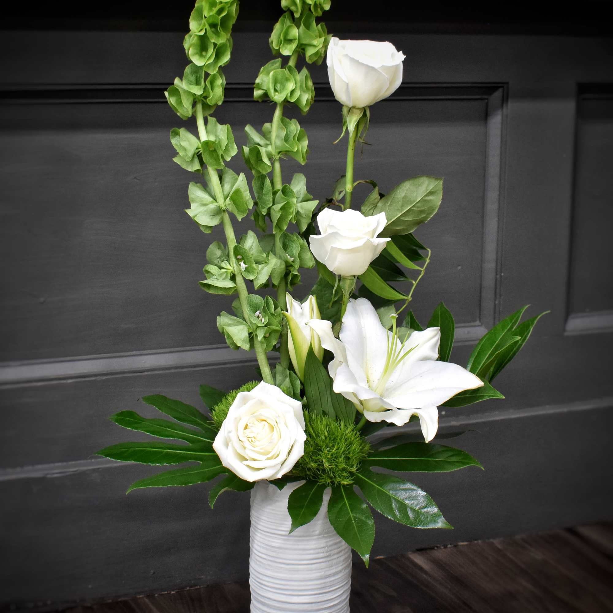 Pure white lilies and roses rise from tall green spikes in a
