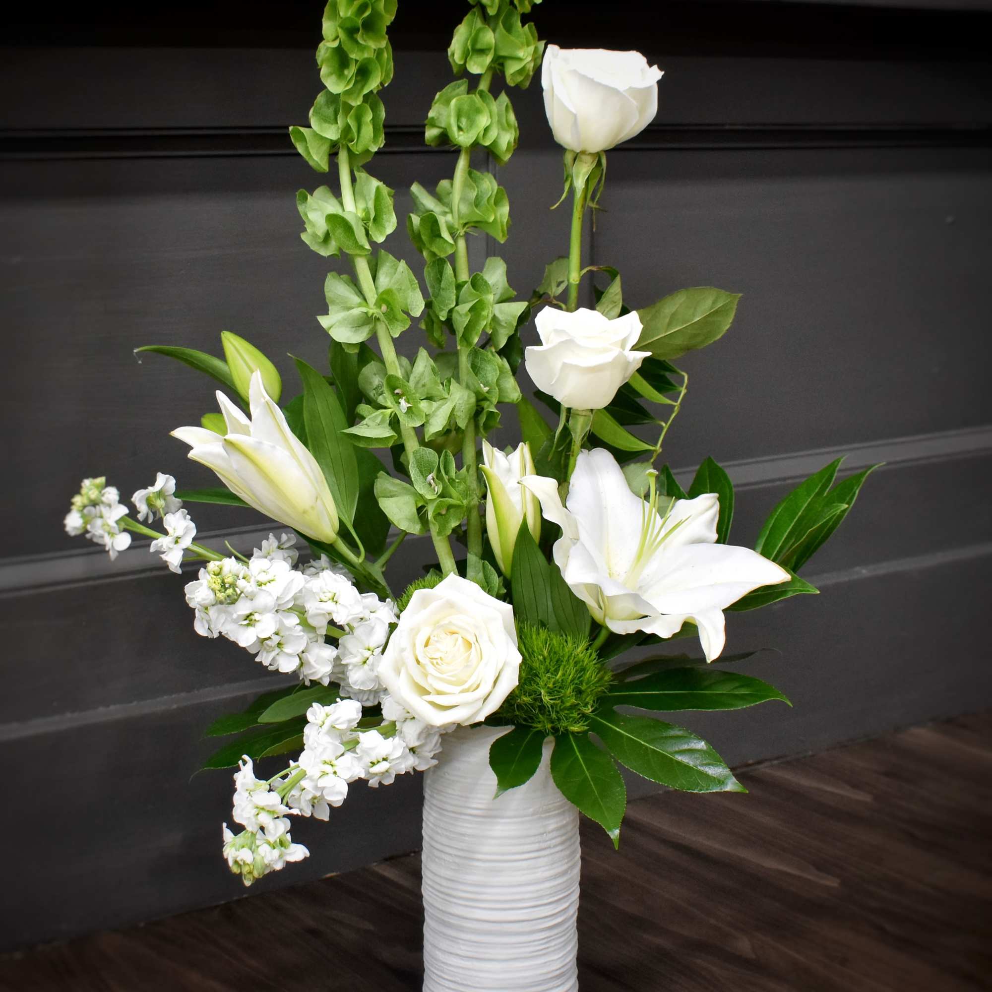 Pure white lilies and roses rise from tall green spikes in a