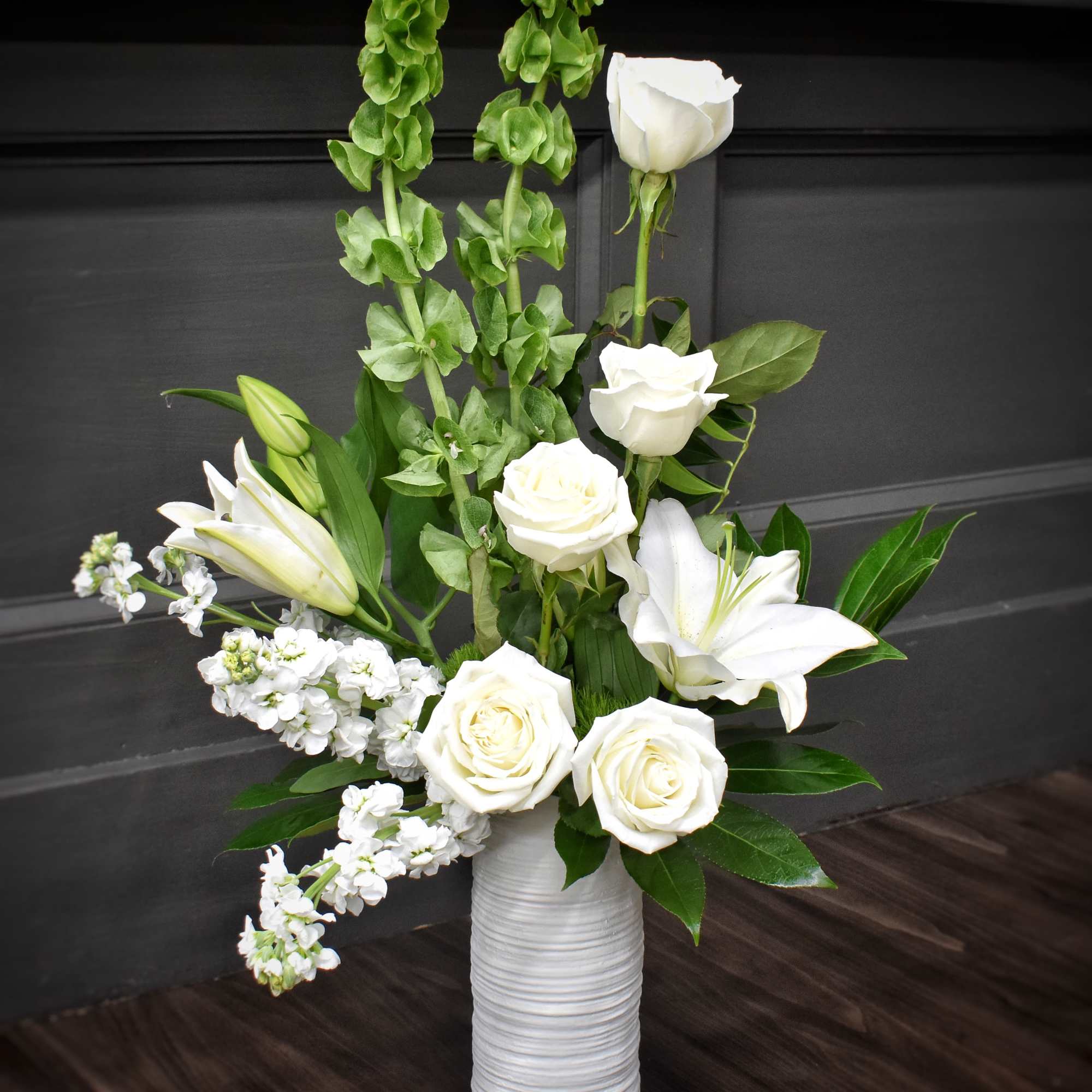 Pure white lilies and roses rise from tall green spikes in a