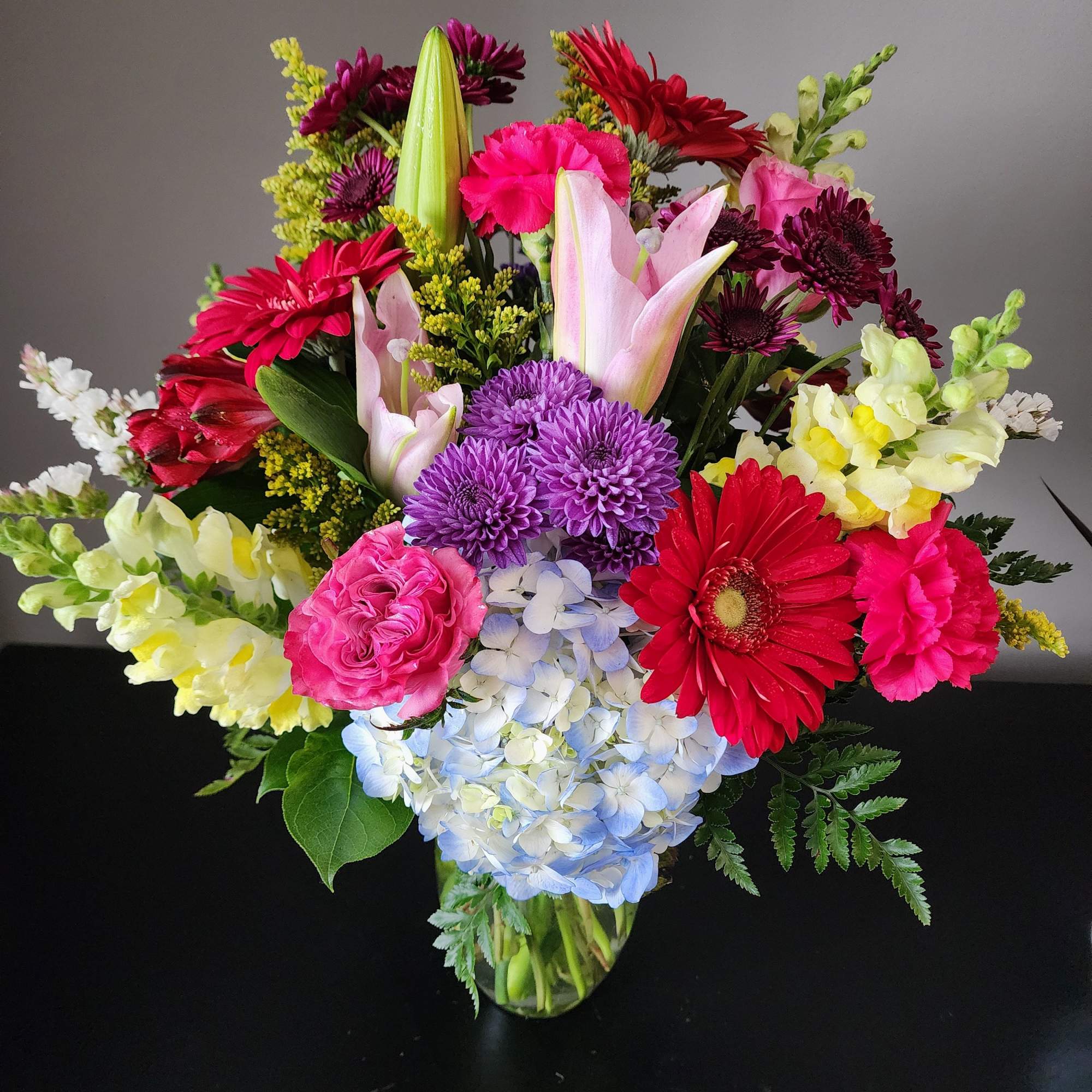 Mixed bouquet in a glass vase with pink, red, purple, and white flowers