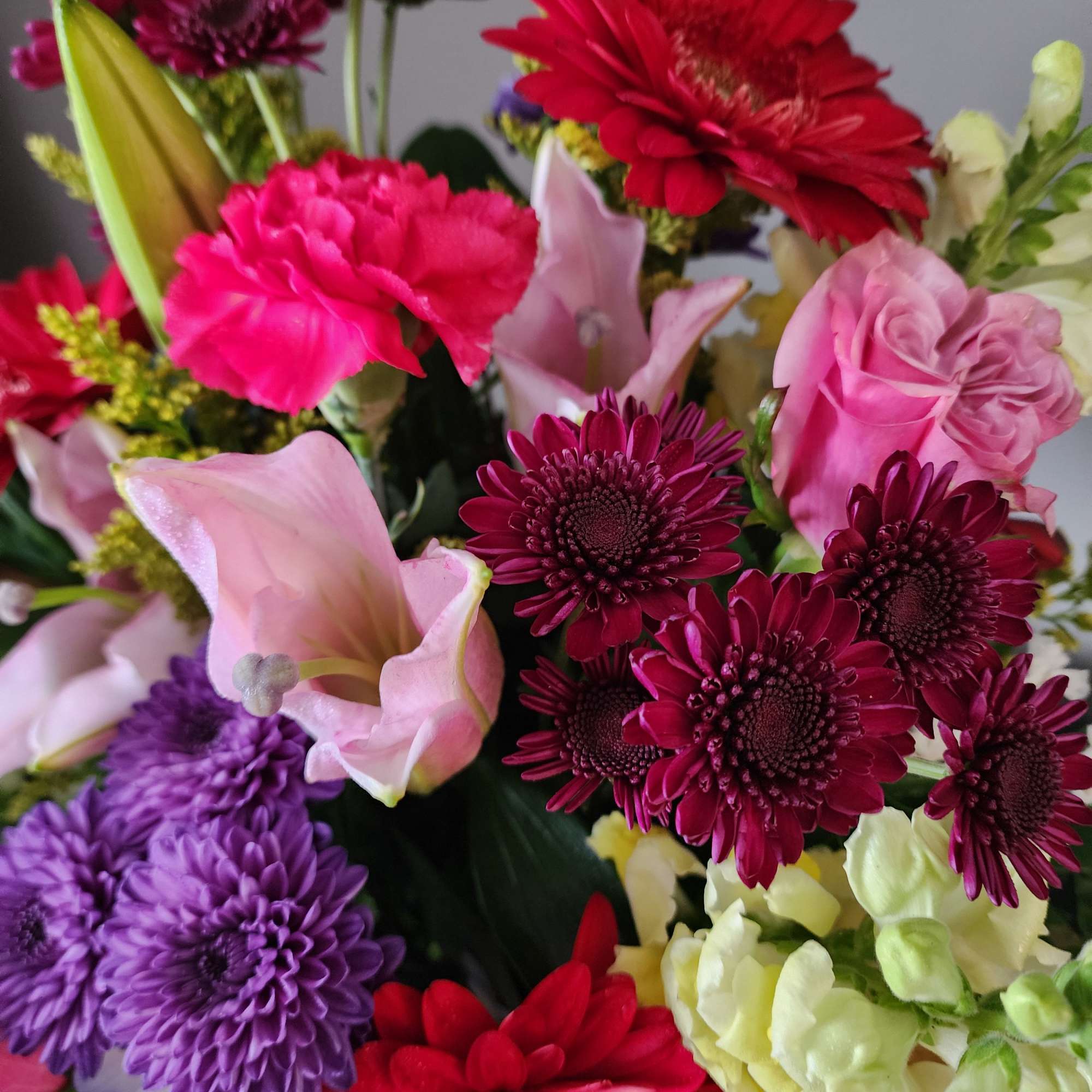 Mixed bouquet with pink and red gerbera daisies, calla lilies, and purple chrysanthemums