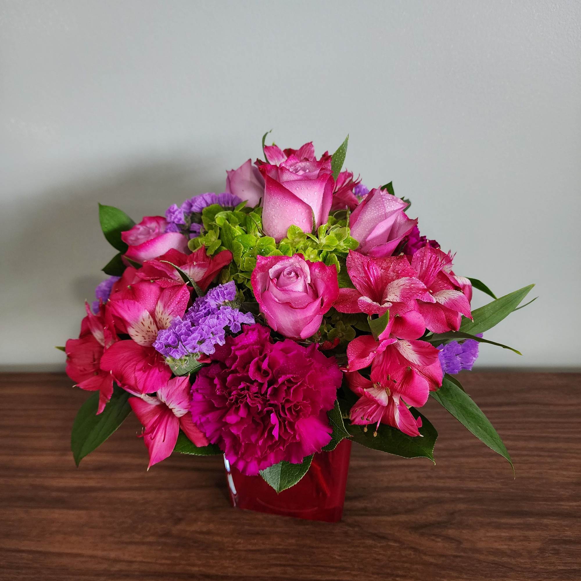 Pink roses and alstroemeria in a red vase