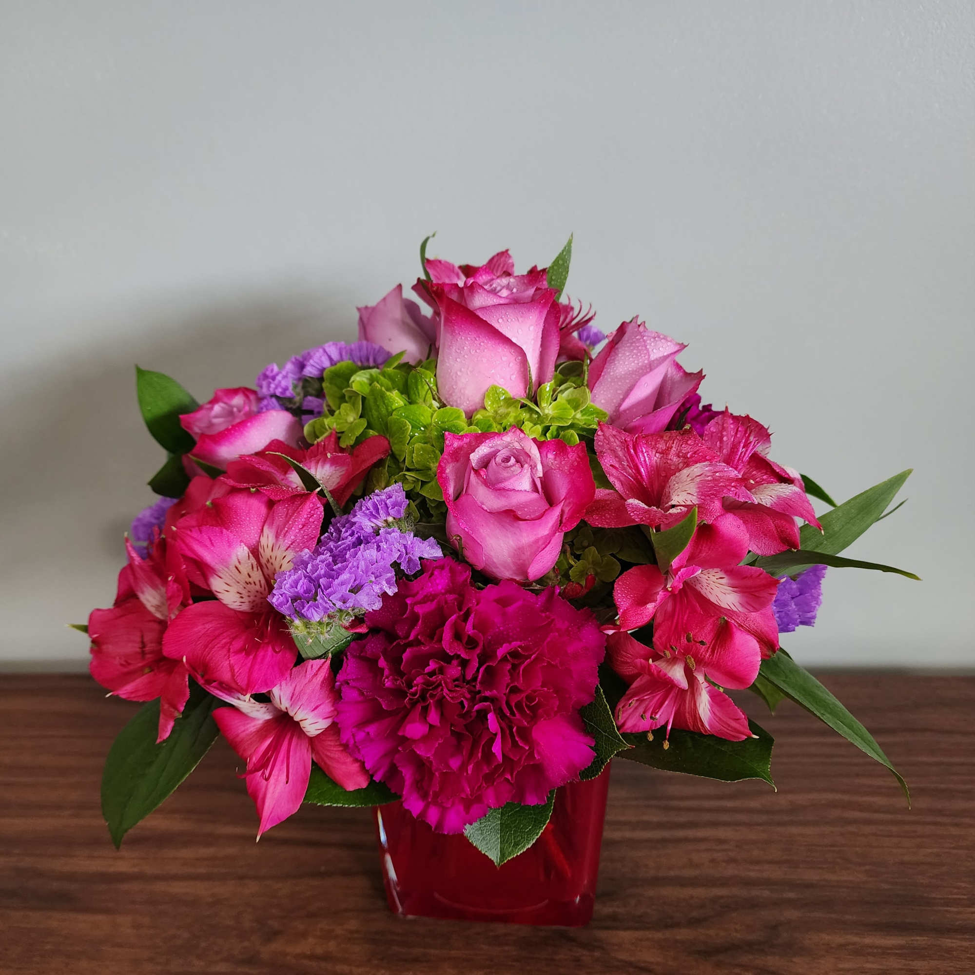 Pink roses and alstroemeria in a red glass vase