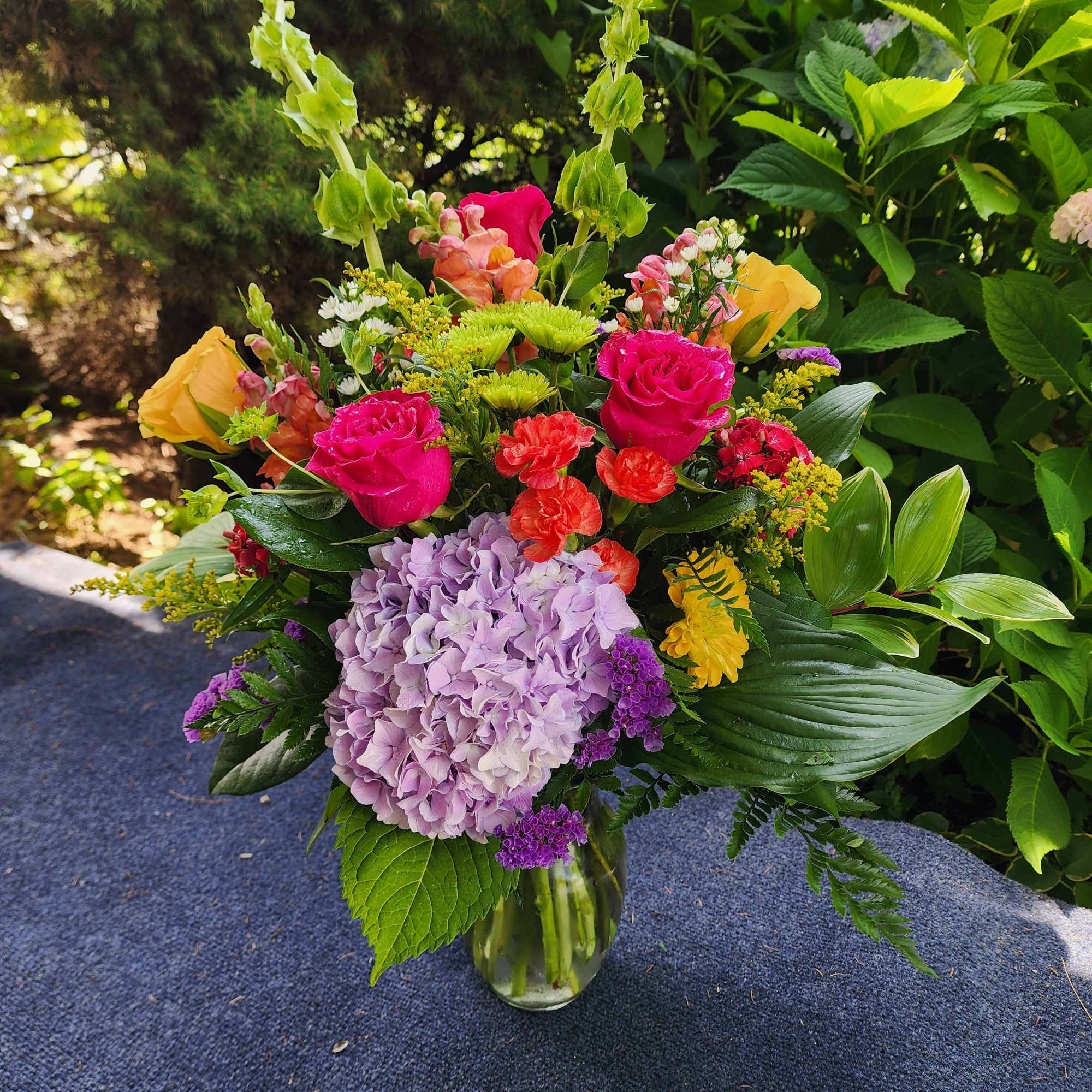 Mixed bouquet in a clear glass vase with pink roses and lavender hydrangea