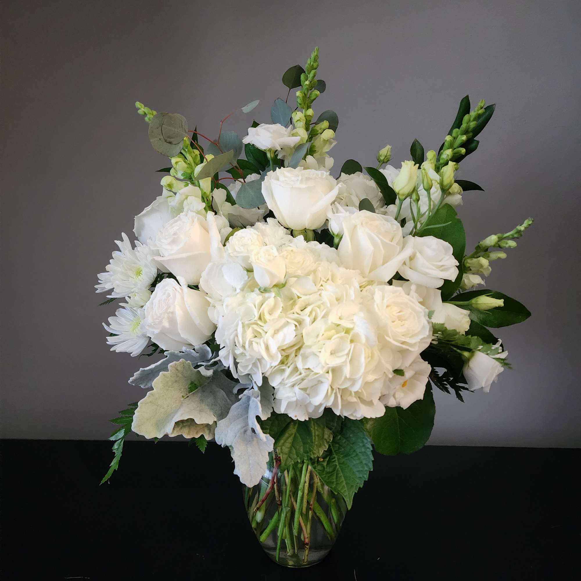 White roses and hydrangeas in a clear glass vase