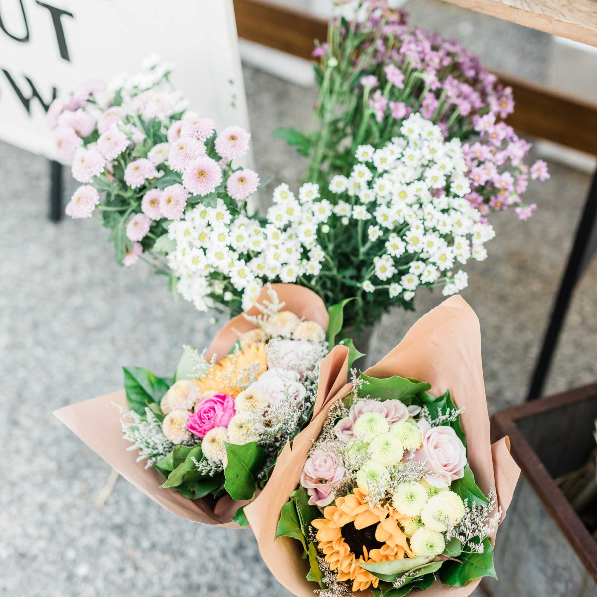 Three wrapped bouquets of mixed pastel flowers on a shop floor