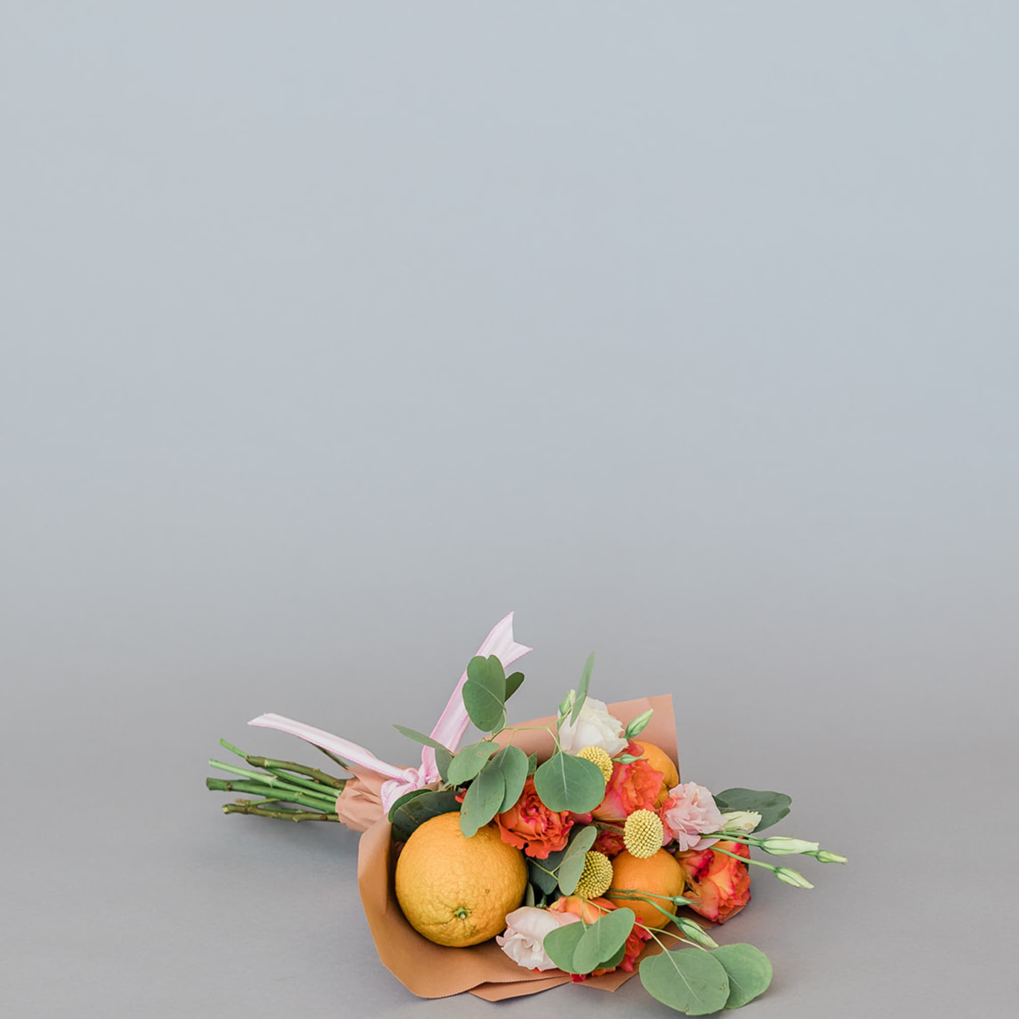 Bouquet with oranges and pink flowers wrapped in peach paper
