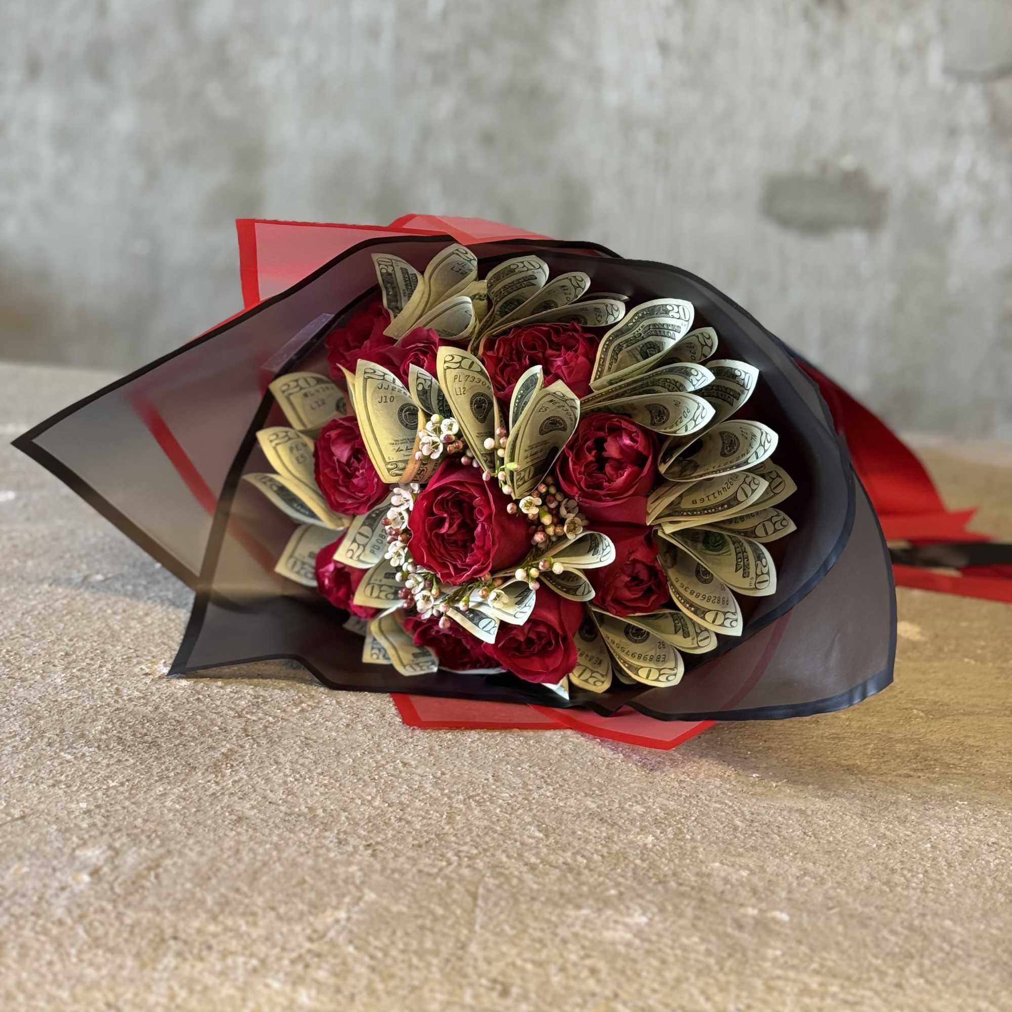 Bouquet of red roses wrapped with folded dollar bills and black paper