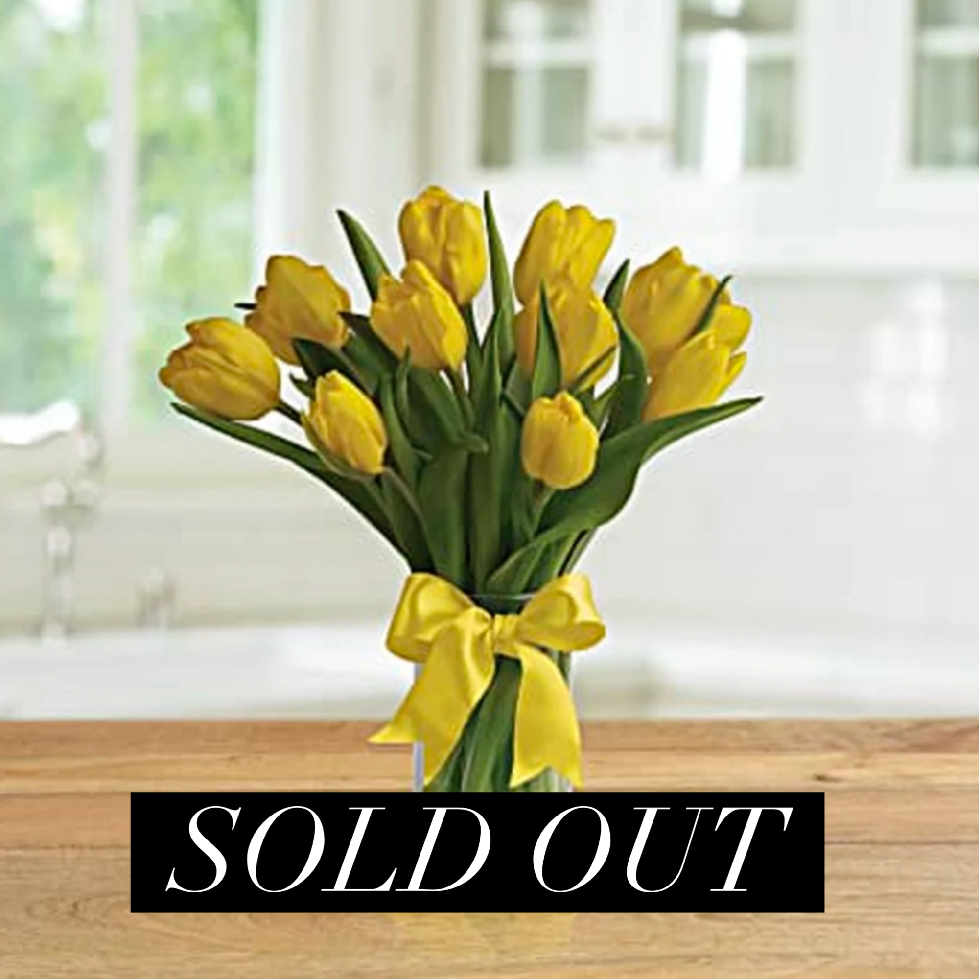 Yellow tulip bouquet tied with a yellow ribbon in a clear vase