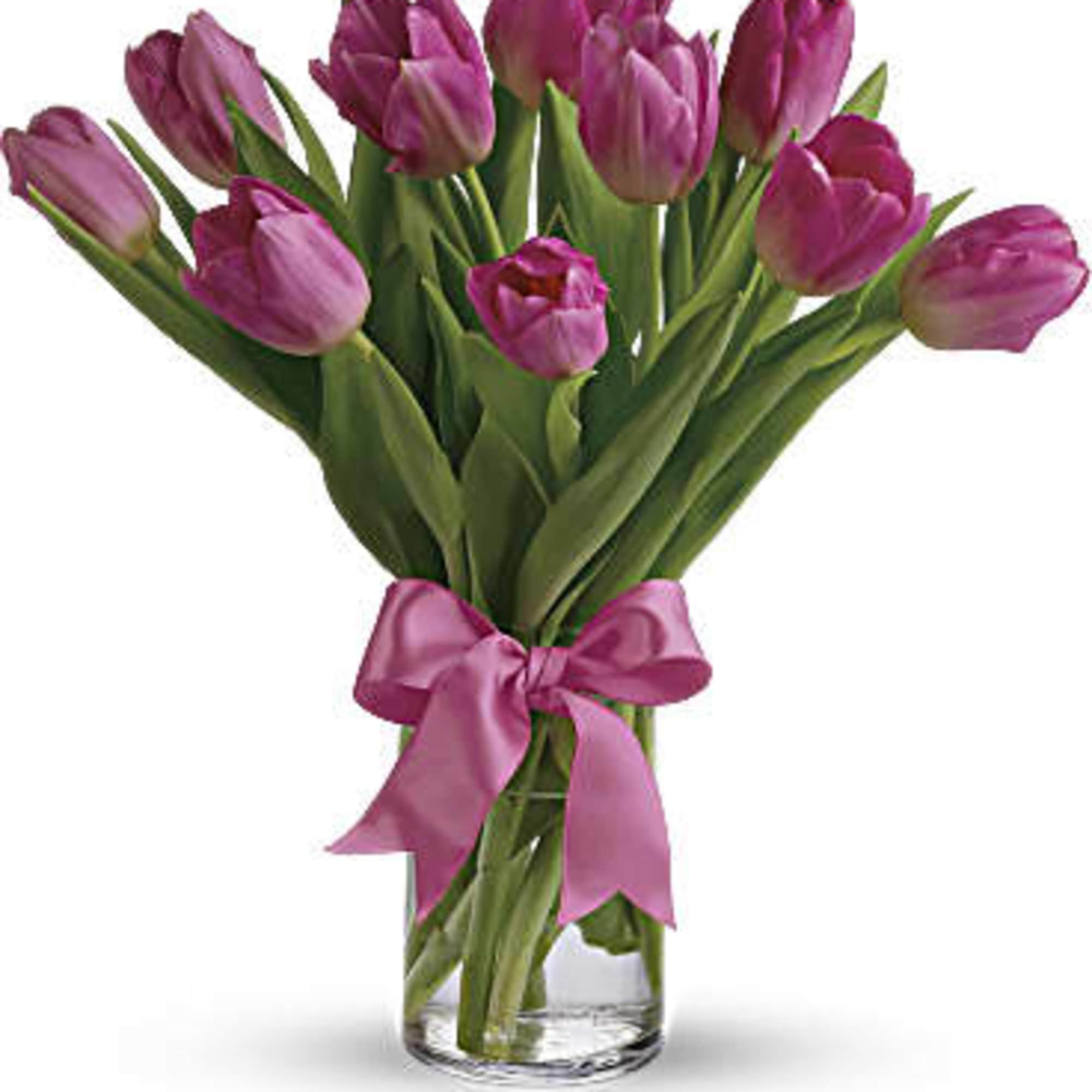 Bouquet of purple tulips tied with a pink ribbon in a clear glass vase