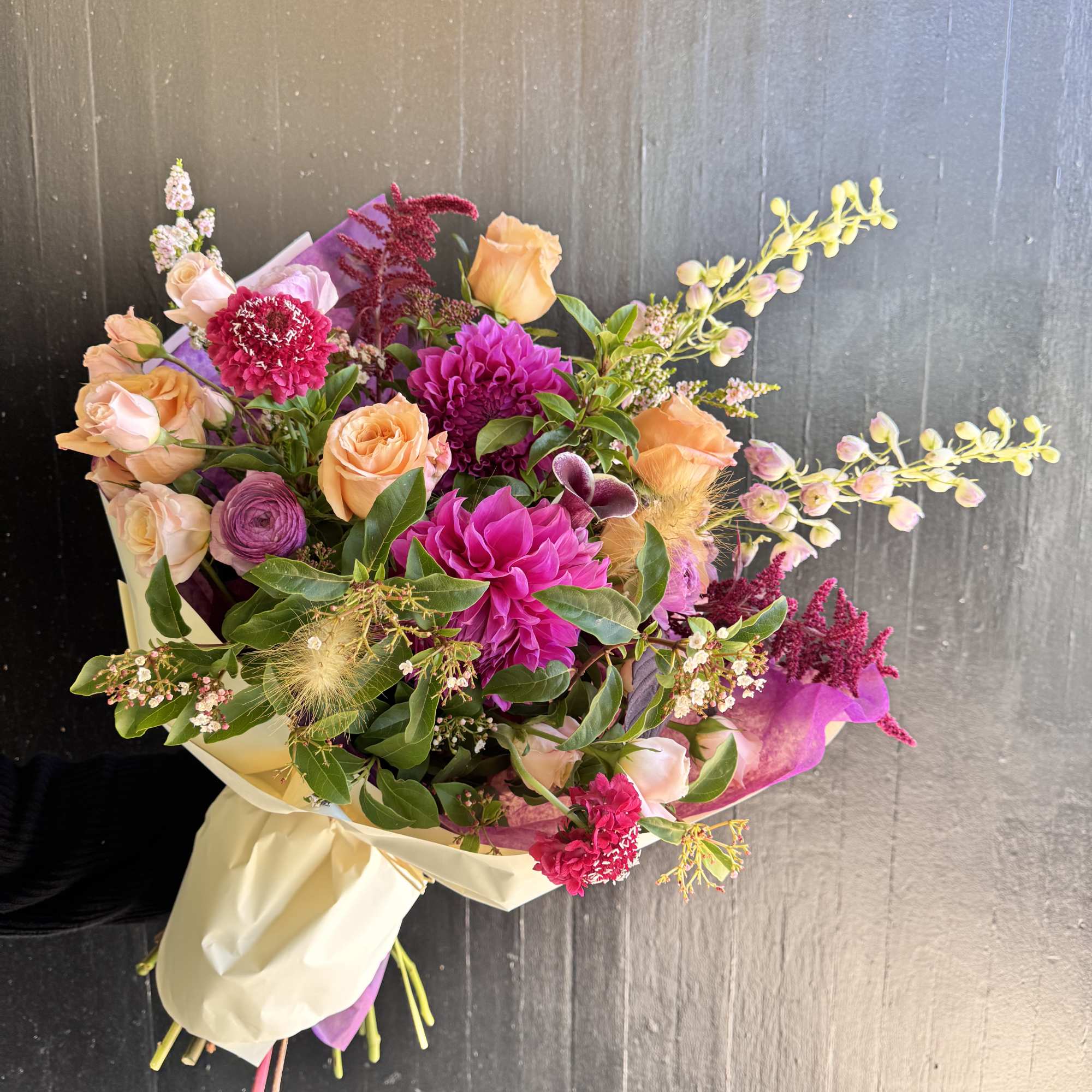 Bouquet of peach and magenta flowers wrapped in cream paper