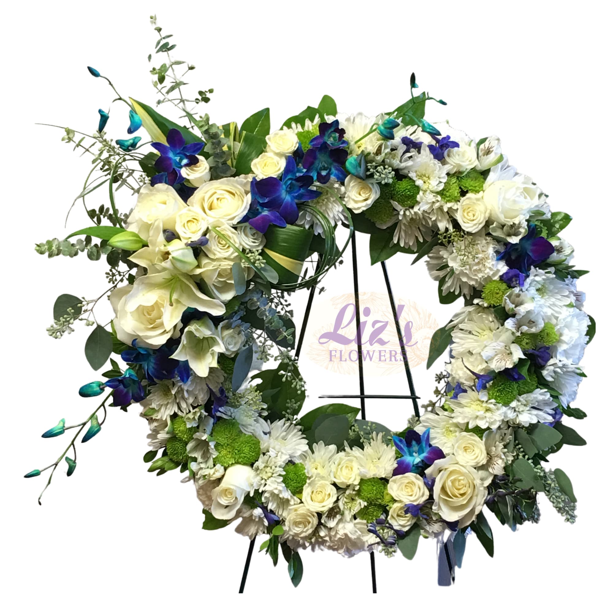 Large white and blue floral wreath with roses, lilies, and orchids on a metal easel stand