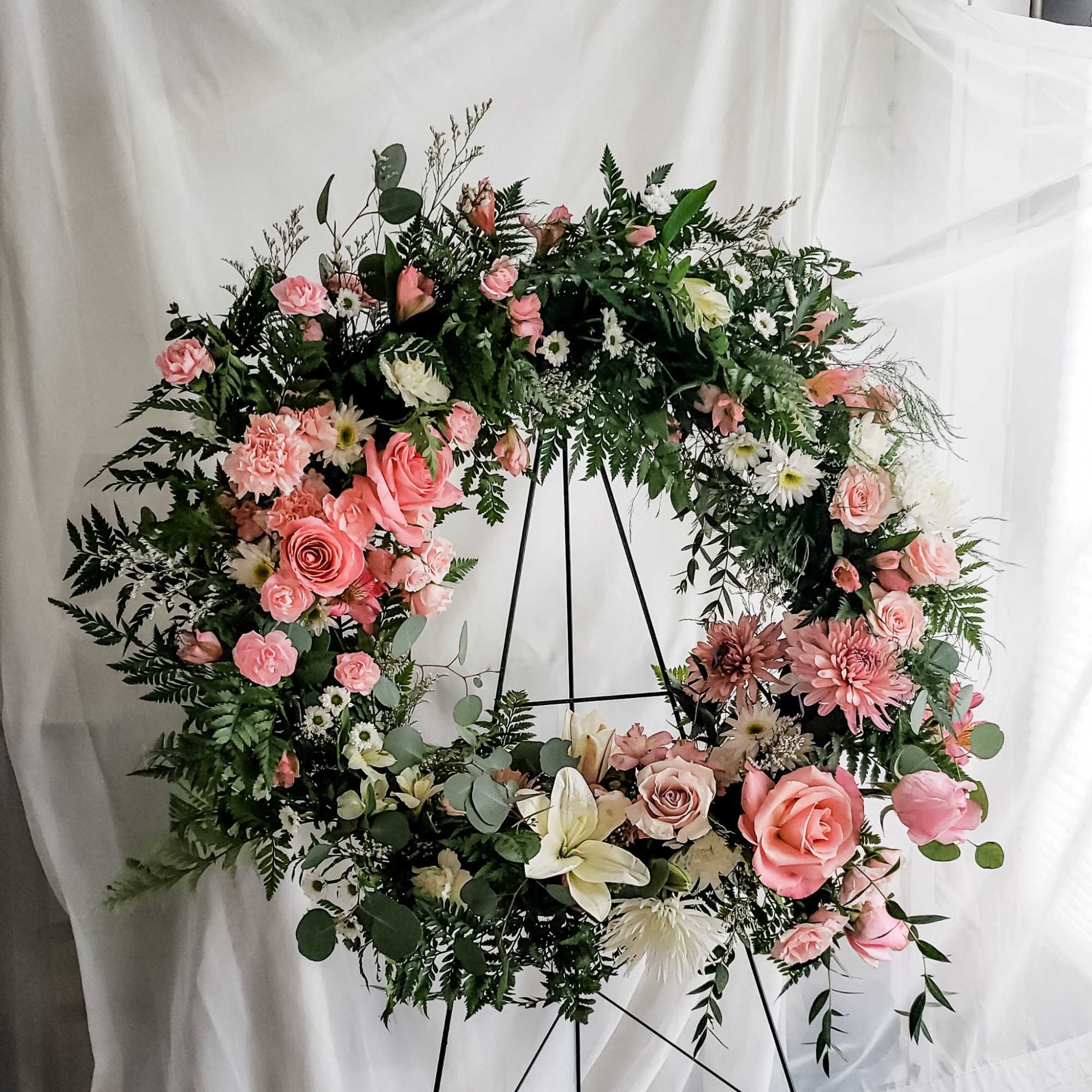 Large floral wreath with pink and white flowers on a black stand