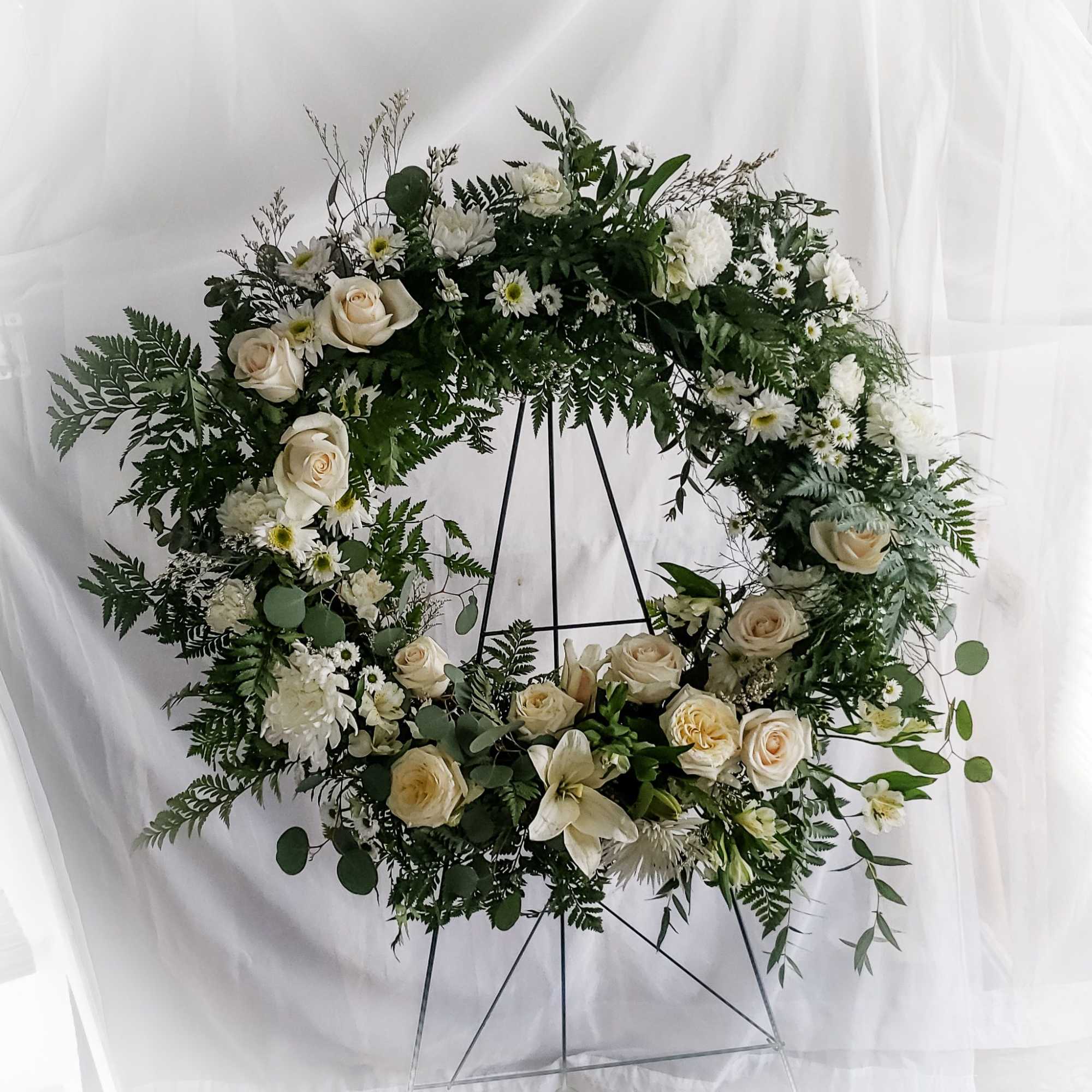 Large floral wreath of white roses and daisies on a metal stand