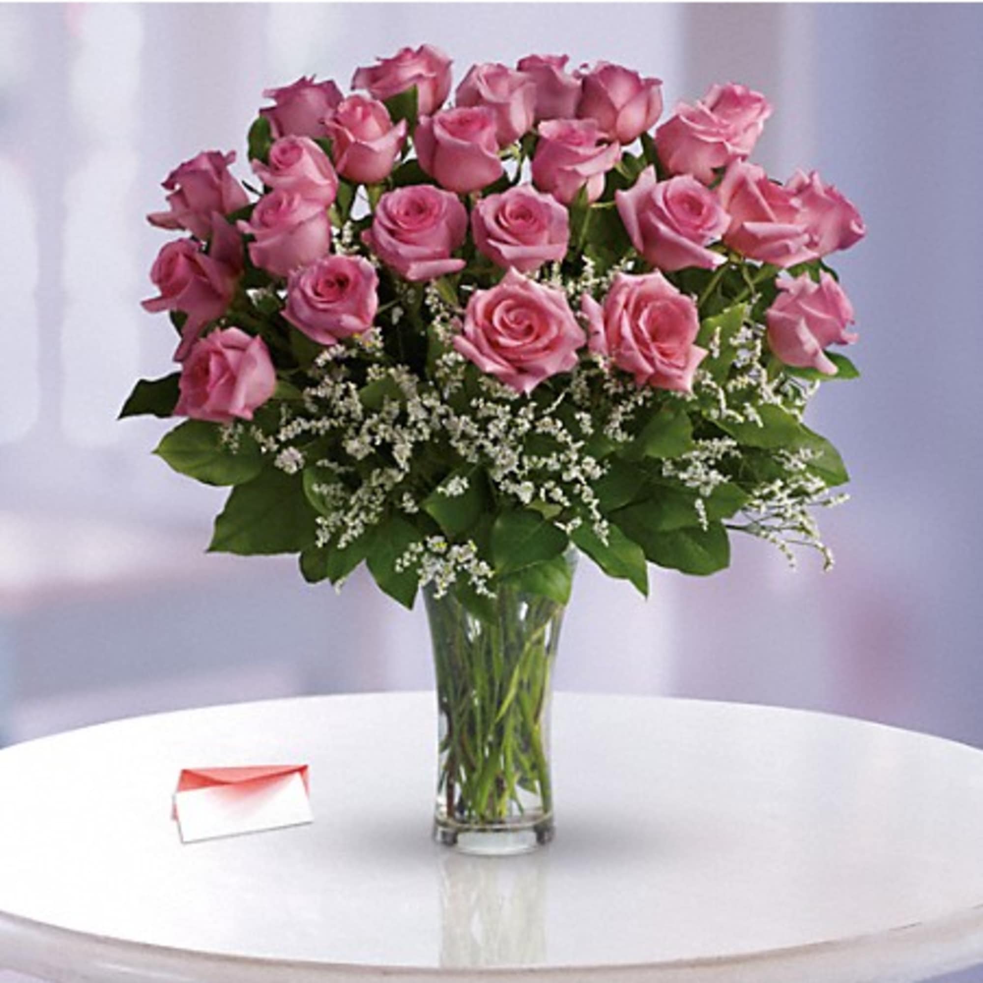 Pink roses arranged in a clear glass vase with white filler flowers