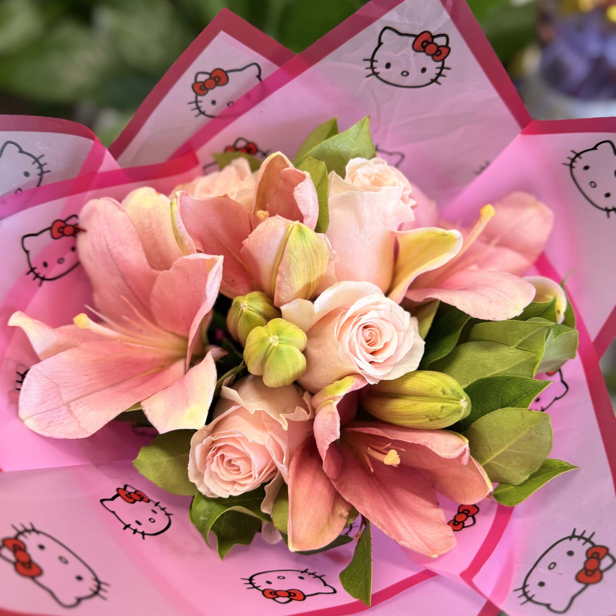 Pink bouquet with roses and lilies wrapped in Hello Kitty paper
