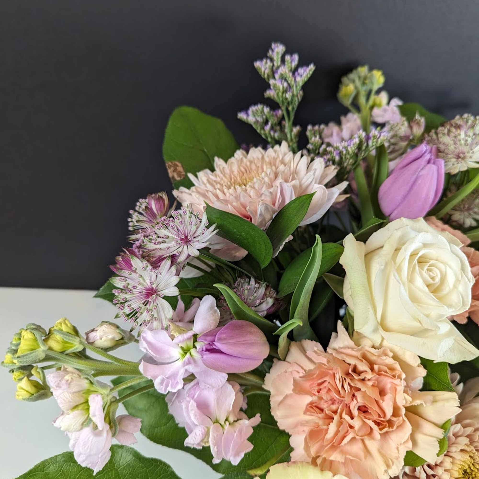 Bouquet of cream, peach, and lavender flowers with roses and carnations