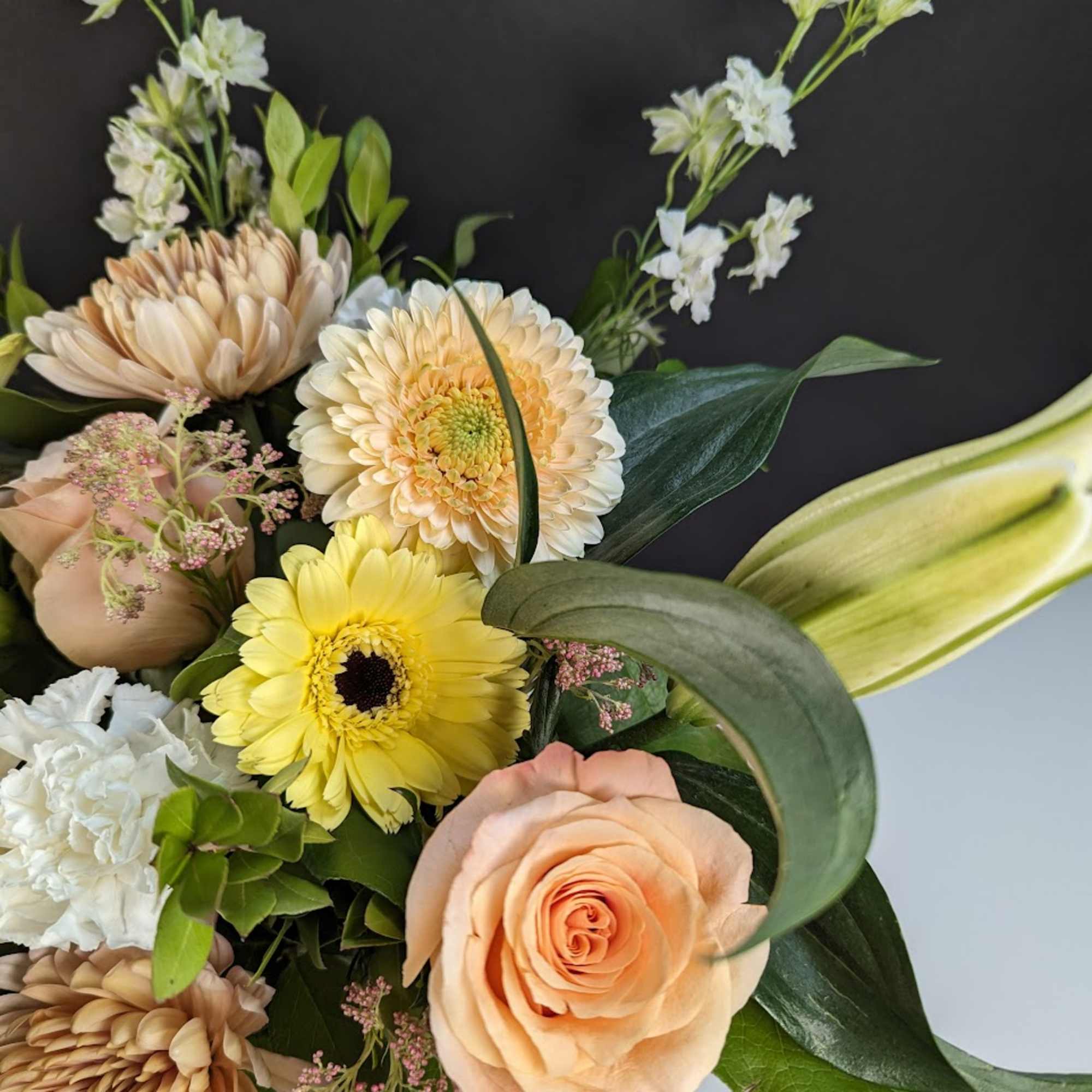 Bouquet of peach roses, yellow gerbera daisies, and white blooms