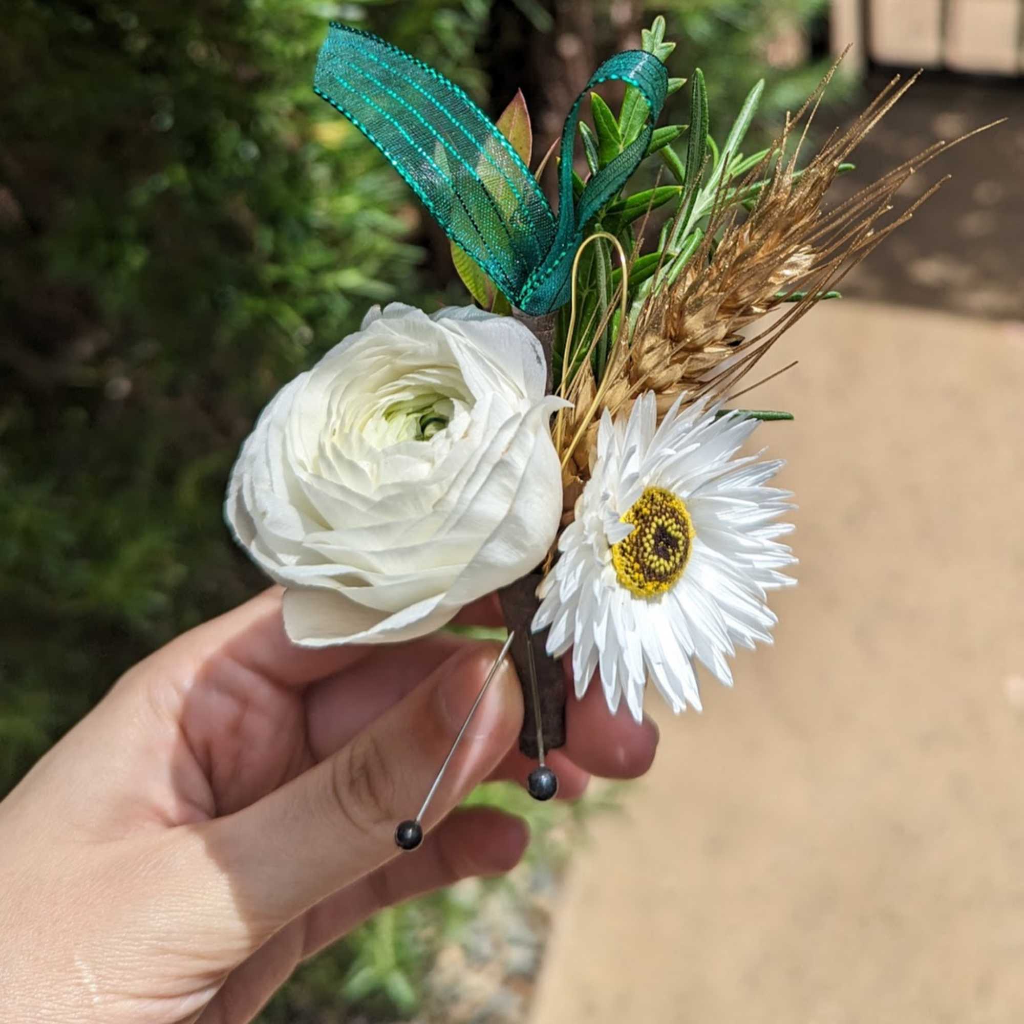 Small boutonniere with white flowers and teal ribbon accents