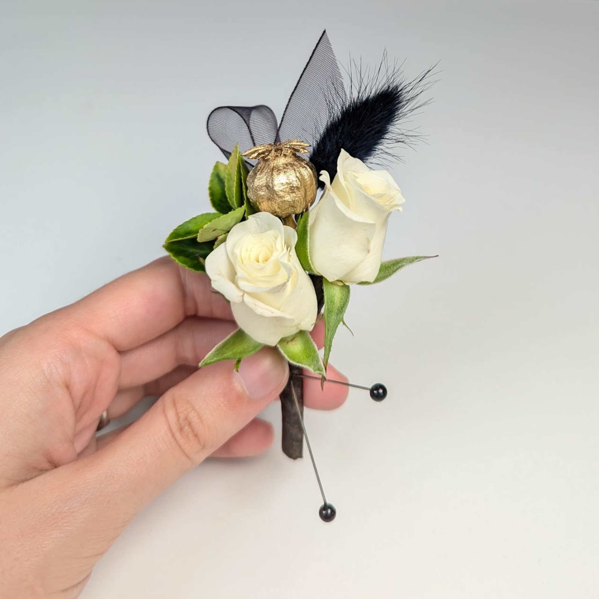 White rose boutonniere with black feather and gold accent