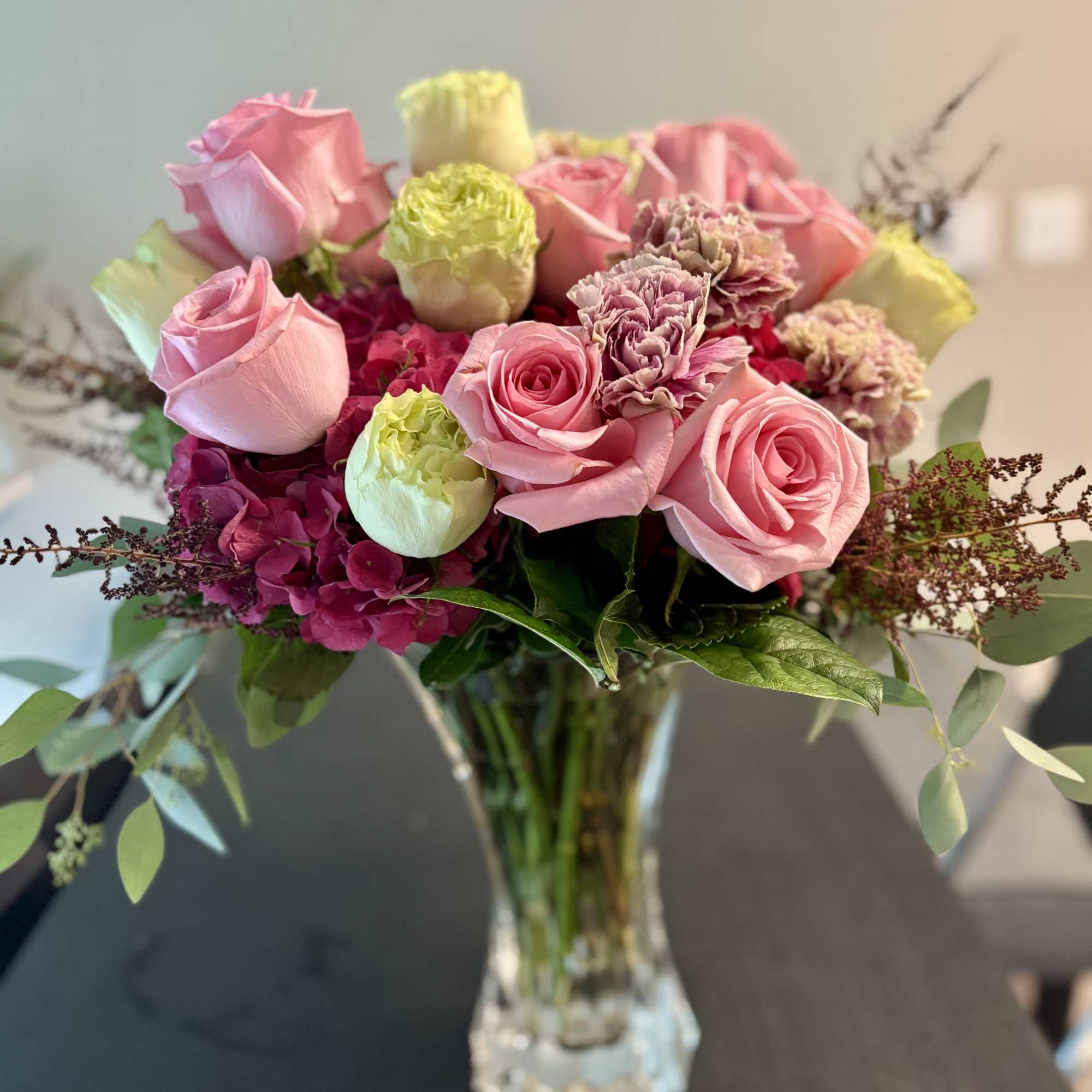 Pink roses and carnations arranged in a clear glass vase, photo 2 of 2