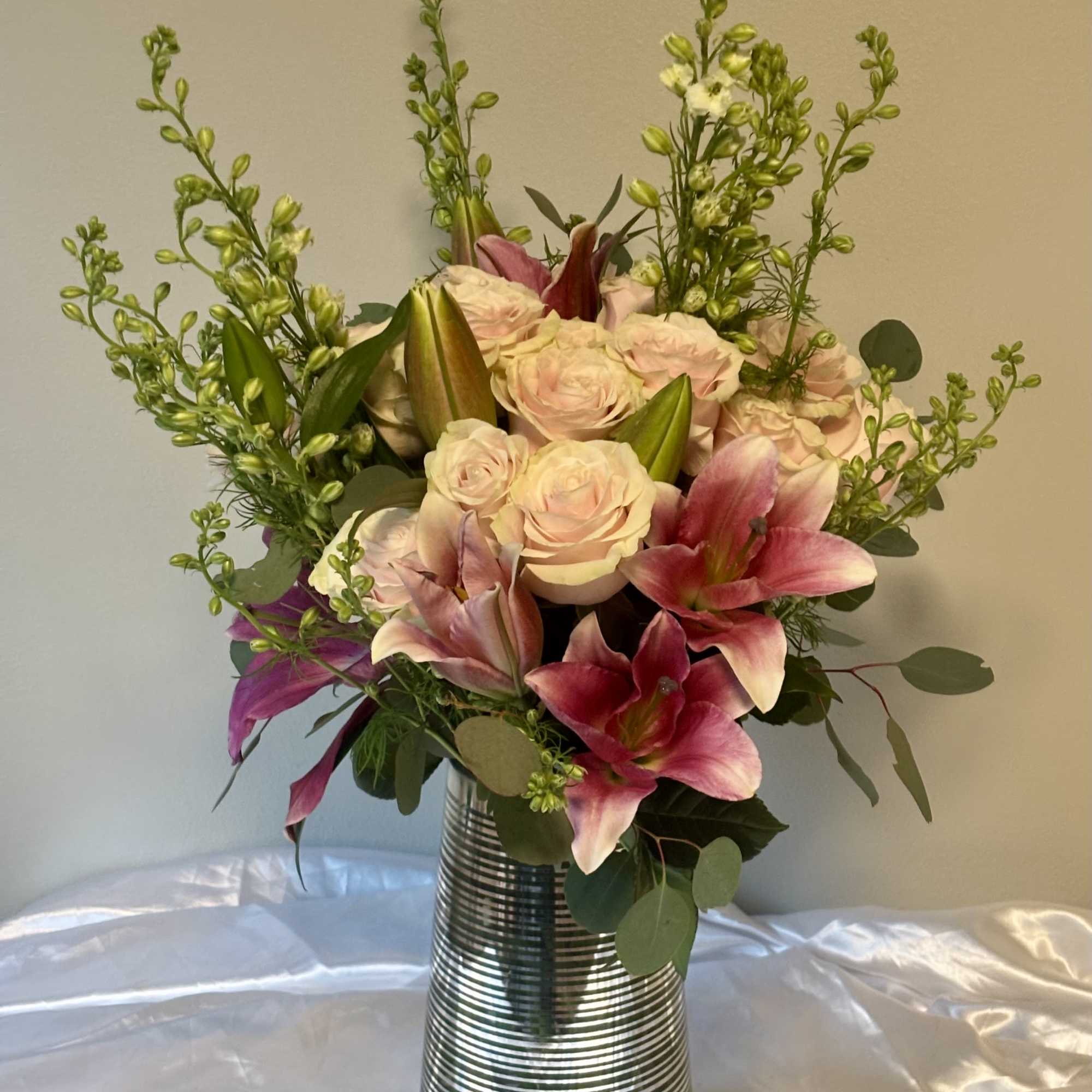 Pink lilies and pale roses in a silver vase
