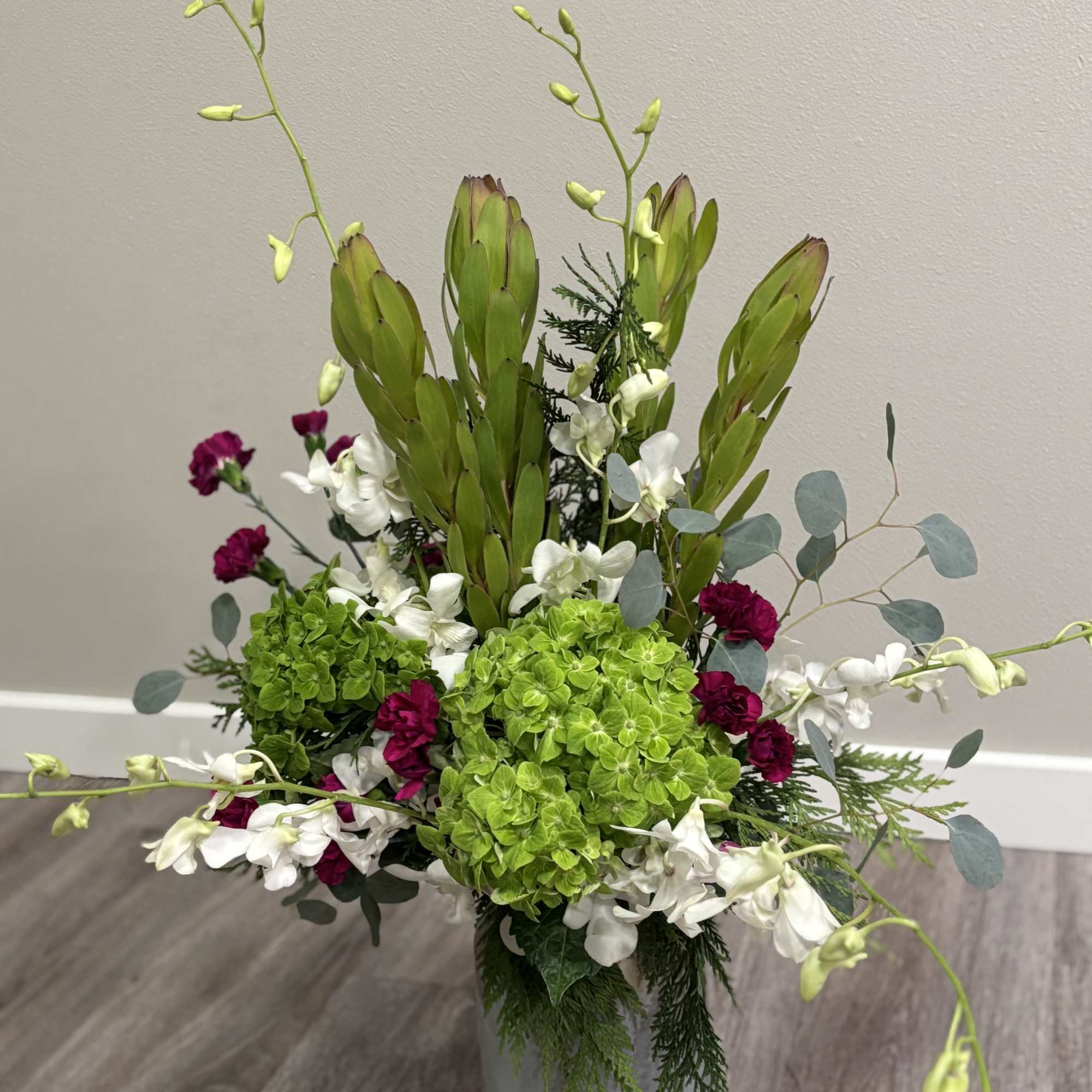 Tall floral arrangement in a gray vase with green, white, and magenta blooms